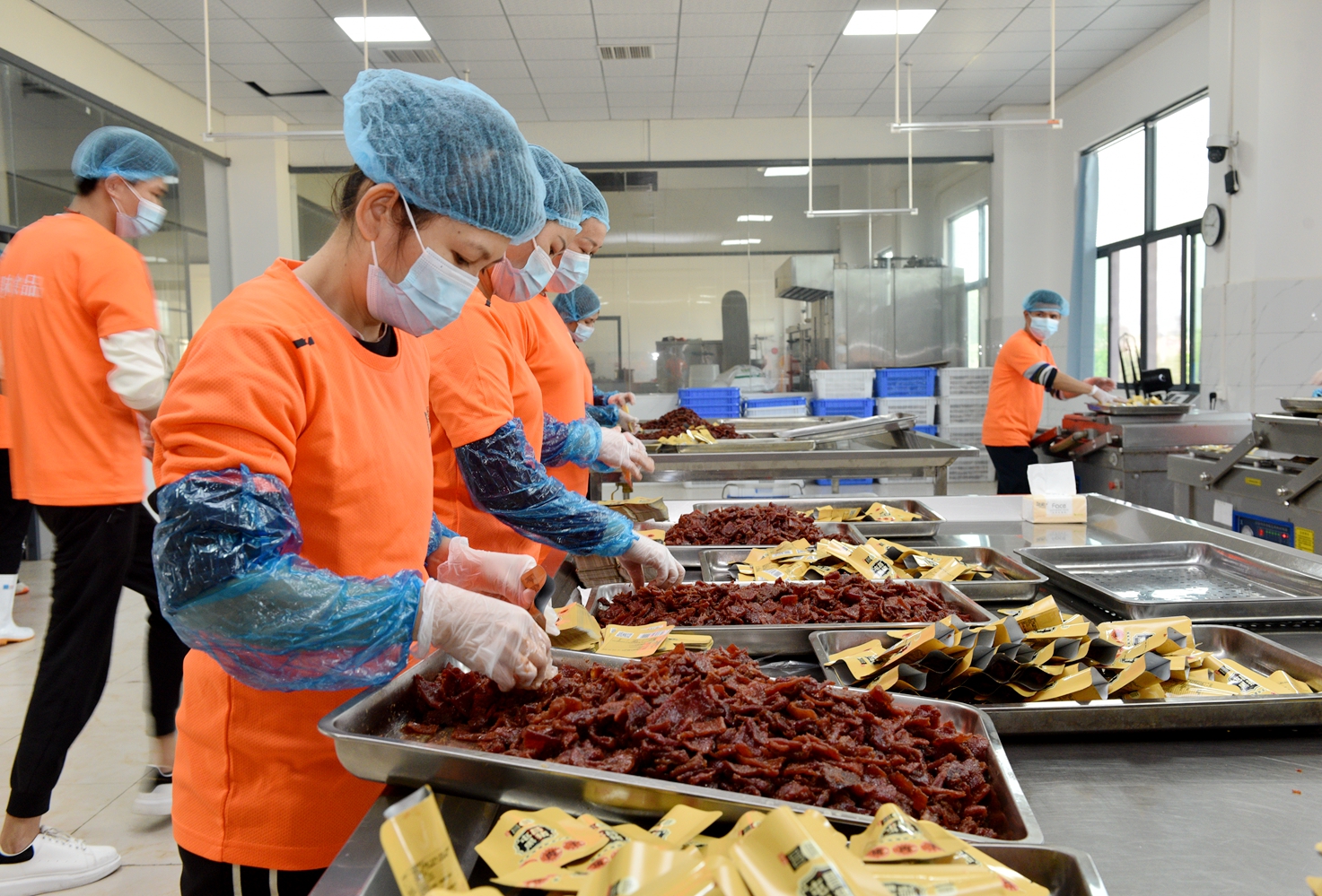 Worker are seen packing cured black pork jerky at a food factory in Tunchang, Hainan Province on January 6, 2025. /Photo provided to CGTN