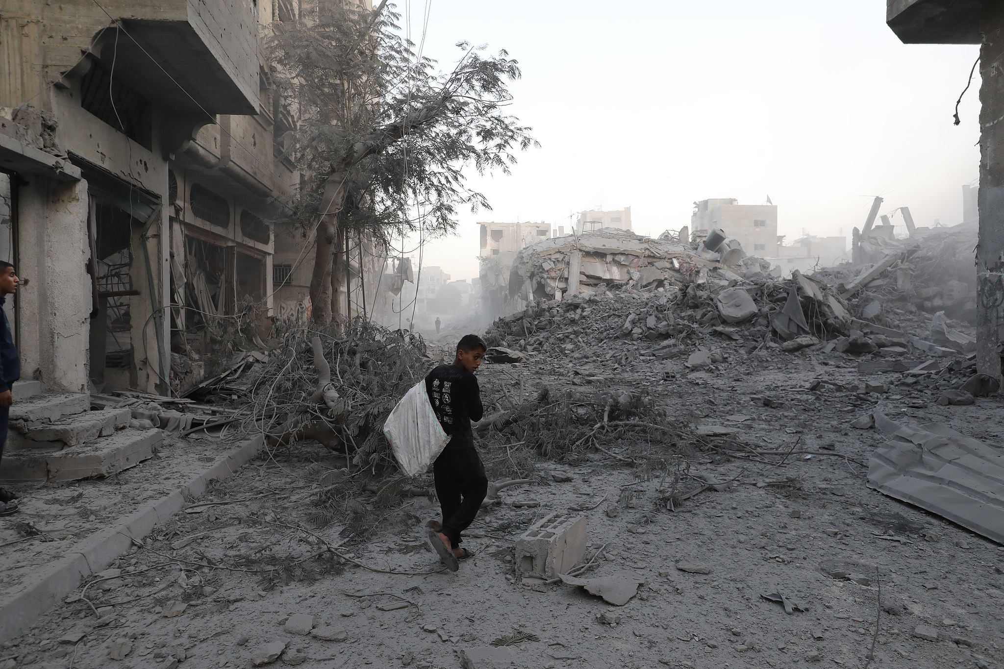 Palestinians leave the area after the Israeli army launched an attack on two buildings in the Bureij Camp, located in the central Gaza Strip, Gaza on January 12, 2025. /CFP