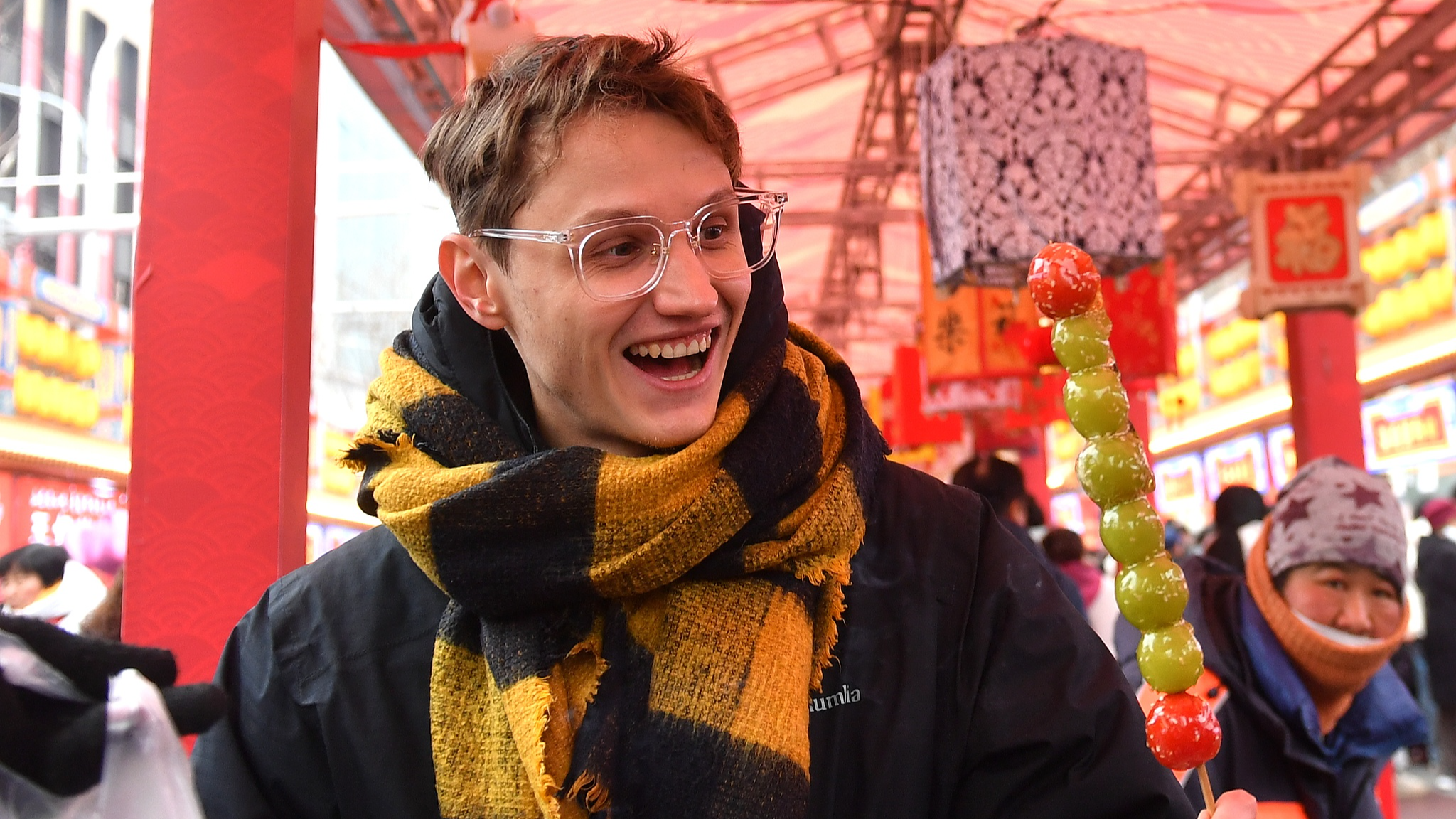 A foreigner poses with a tanghulu, a sugar-coated traditional Chinese snack, at a temple fair in Qingdao City, east China's Shandong Province, January 31, 2025. /CFP