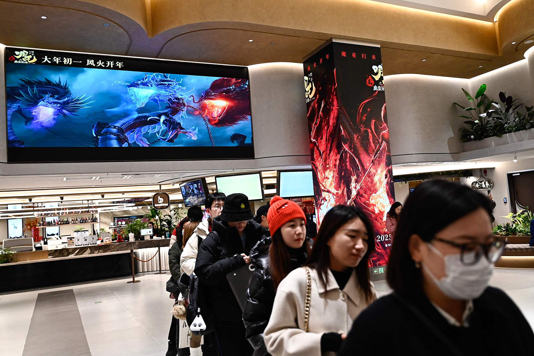 Moviegoers queue as a screen shows scenes from animated film 