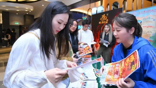 A moviegoer talks with a staff worker at a "China Travel with Chinese Films" campaign in  the Macao SAR, February 22, 2025. /CMG