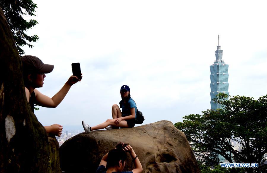 Tourists take photos with the Taipei 101 skyscraper in the background at Xiangshan Mountain in Taipei, southeast China's Taiwan, July 21, 2019. /Xinhua
