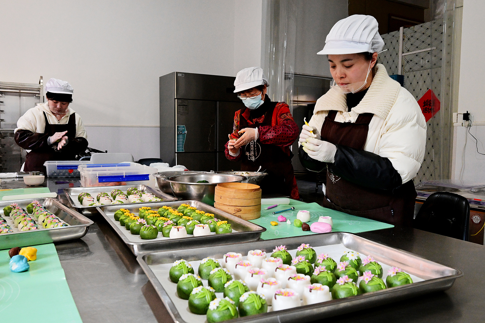 Staff members make Qingming rice cakes at a workshop in Jinhua, Zhejiang Province on March 18, 2025. /VCG