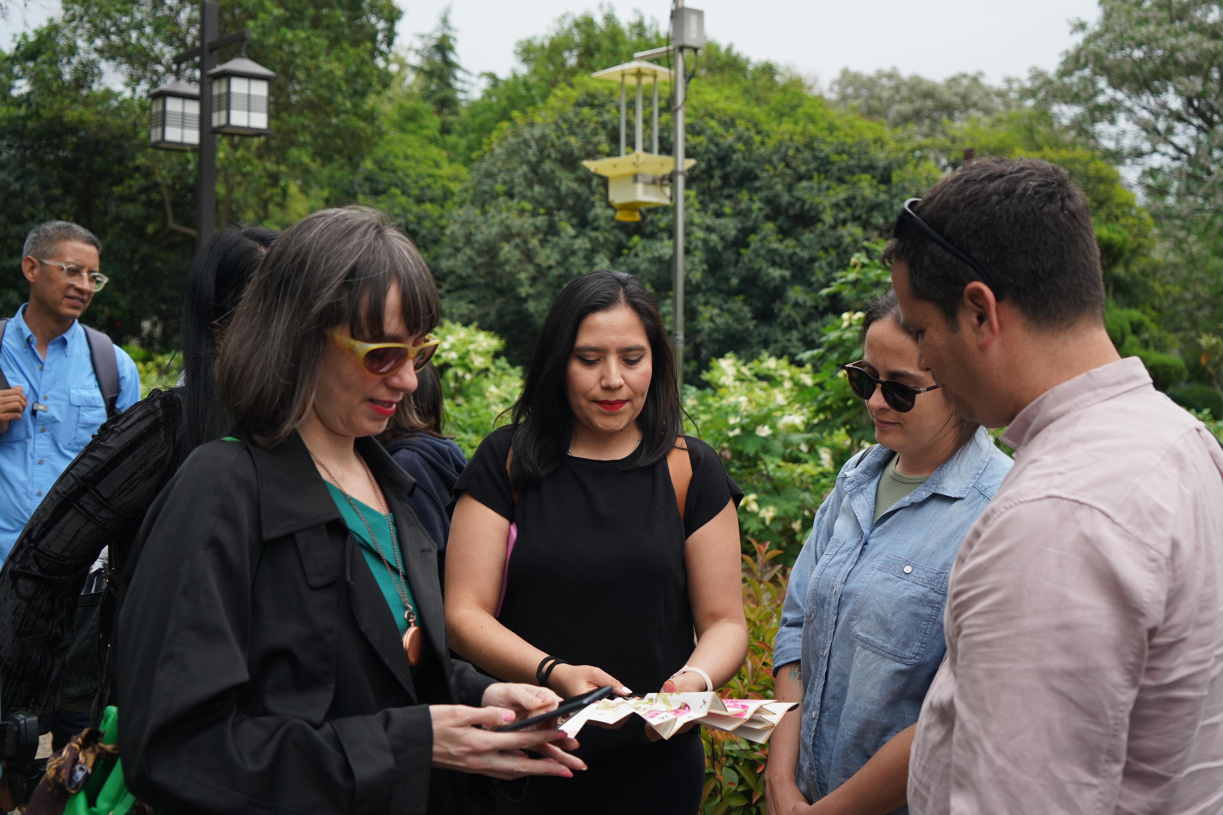 Journalists discuss a paper fan bearing peony paintings at the Luoyang National Peony Garden in central China's Henan Province on April 21, 2025. /CGTN