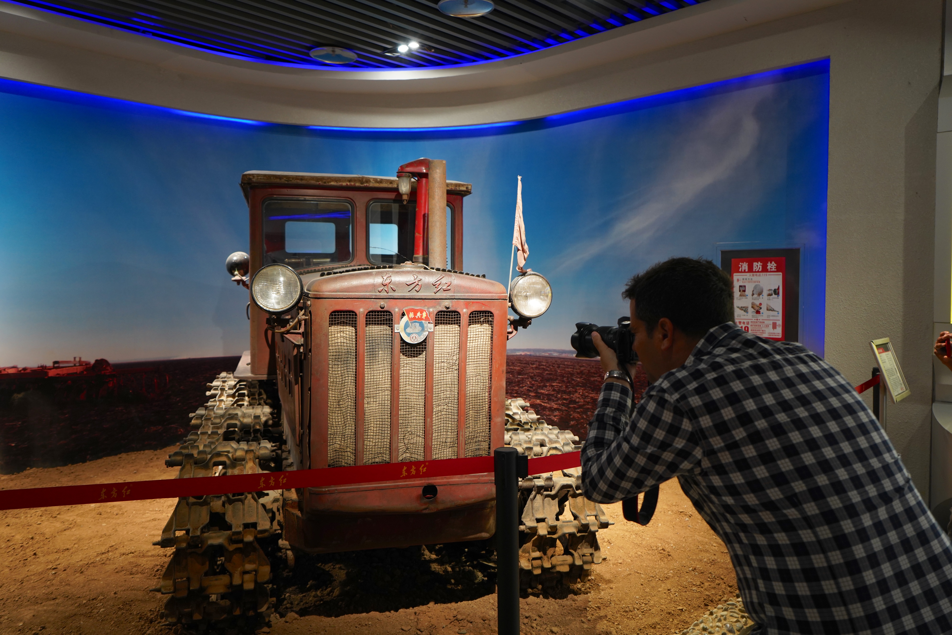 A member of the Latin America and Caribbean media delegation takes photos of a Dongfanghong tractor at the YTO Agriculture Cultivation Museum in Luoyang, Henan Province on April 22, 2025. /CGTN