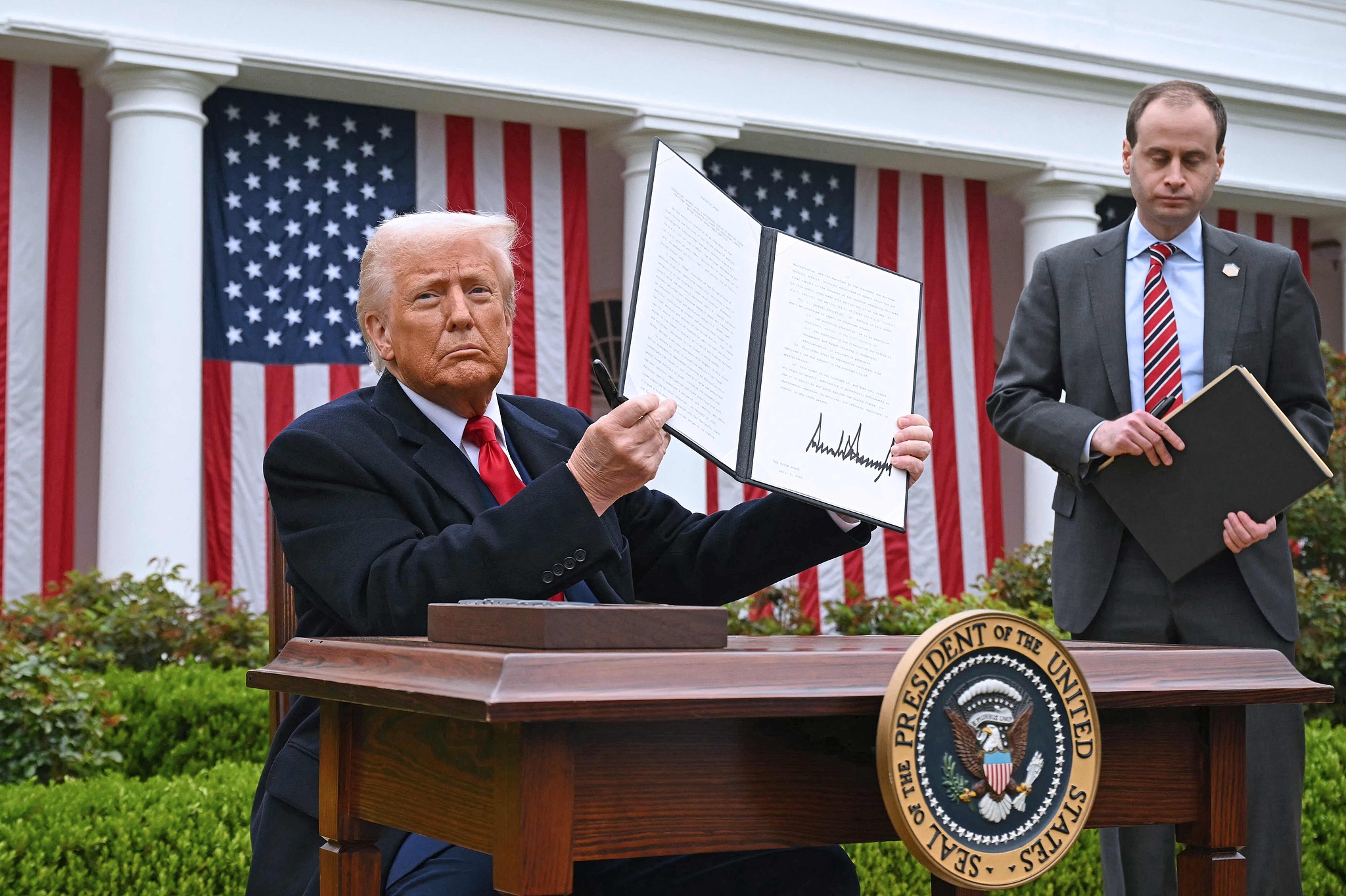 US President Donald Trump holds a signed executive order after delivering remarks on 