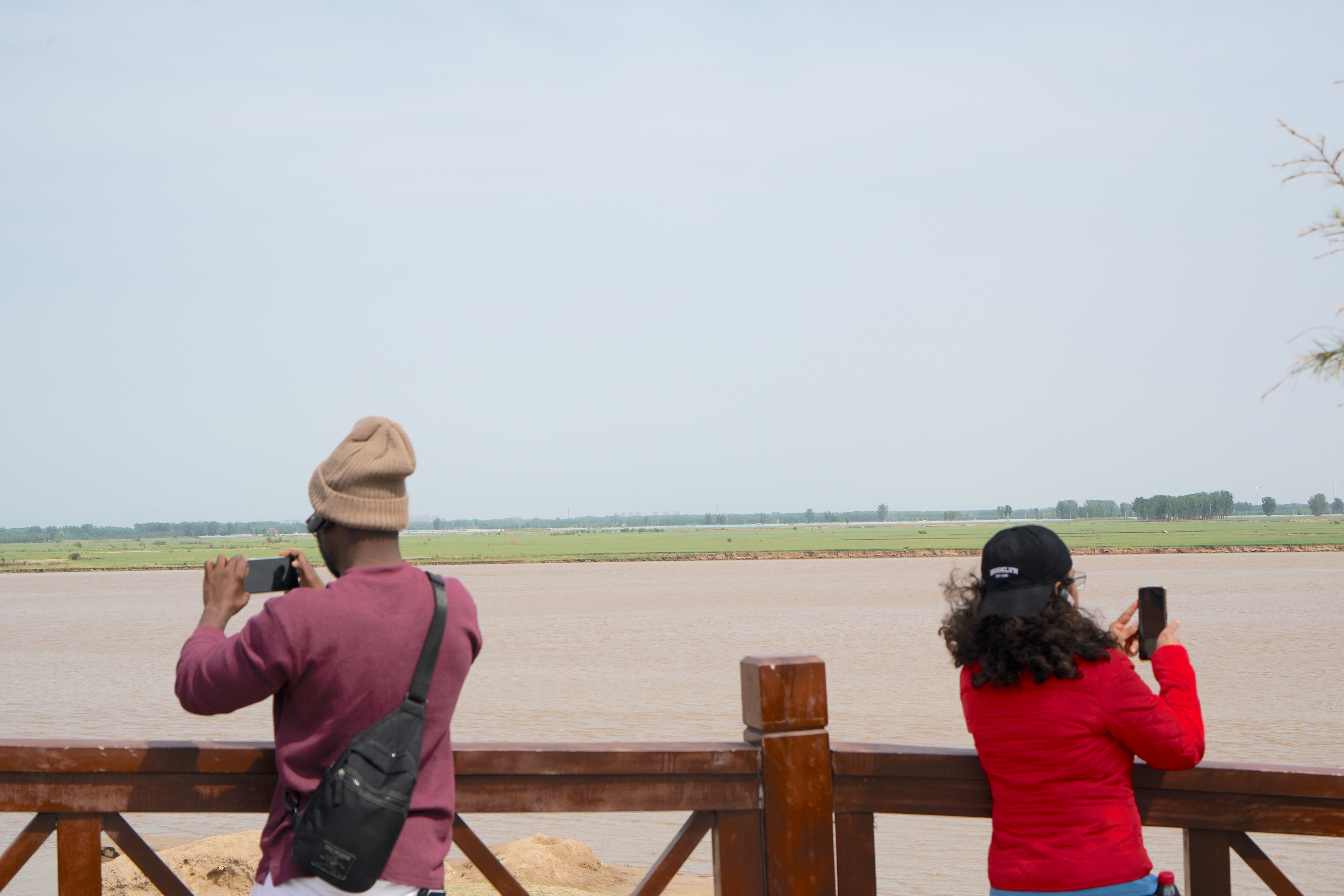 Members of a Latin American and Caribbean media delegation take photos of the Yellow River near Madu Village in Zhengzhou, Henan Province on April 24, 2025. /CGTN