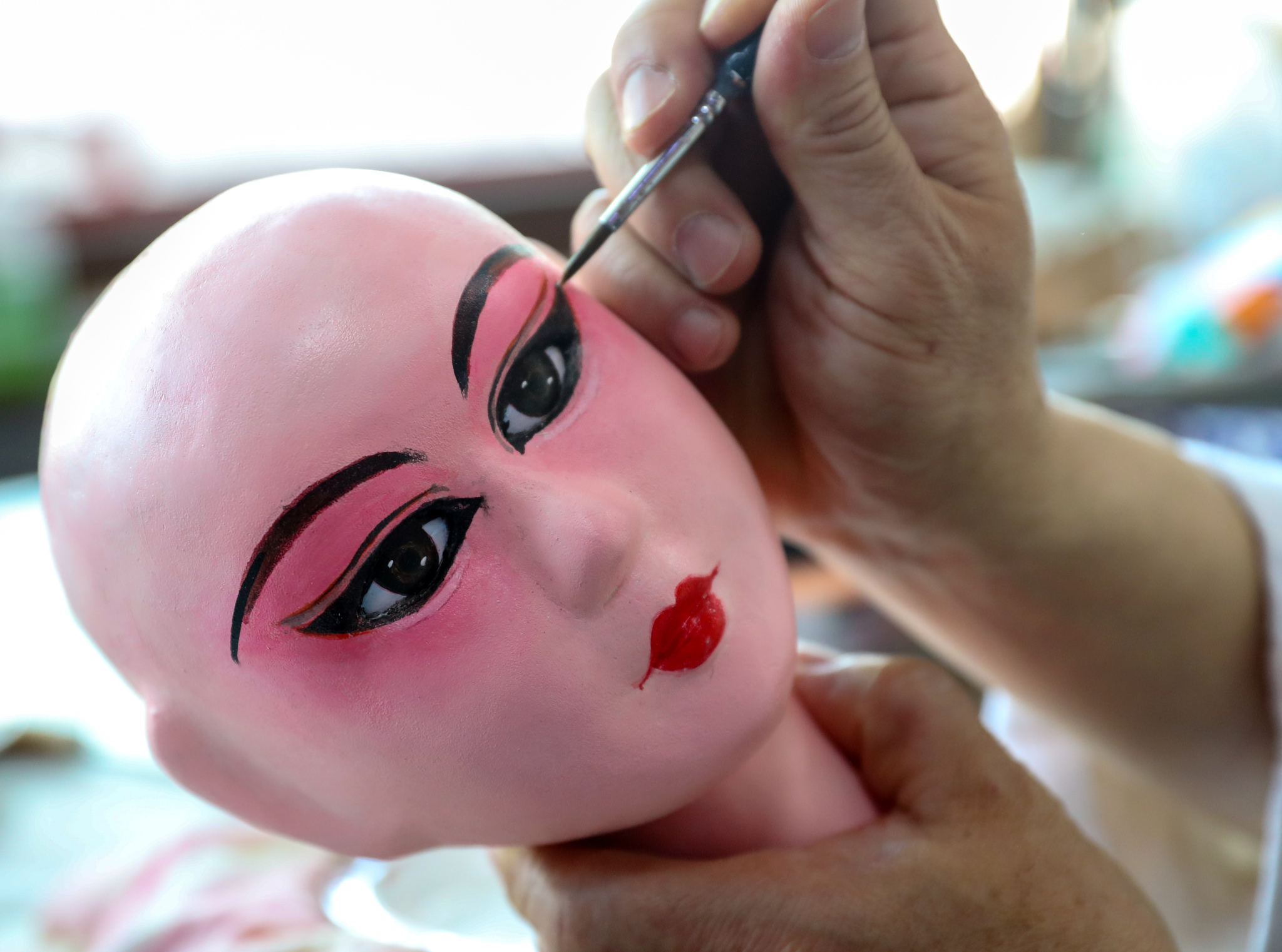 Jiang Yutao applies make-up to a puppet in Qingdao, Shandong Province on May 11, 2025. /VCG