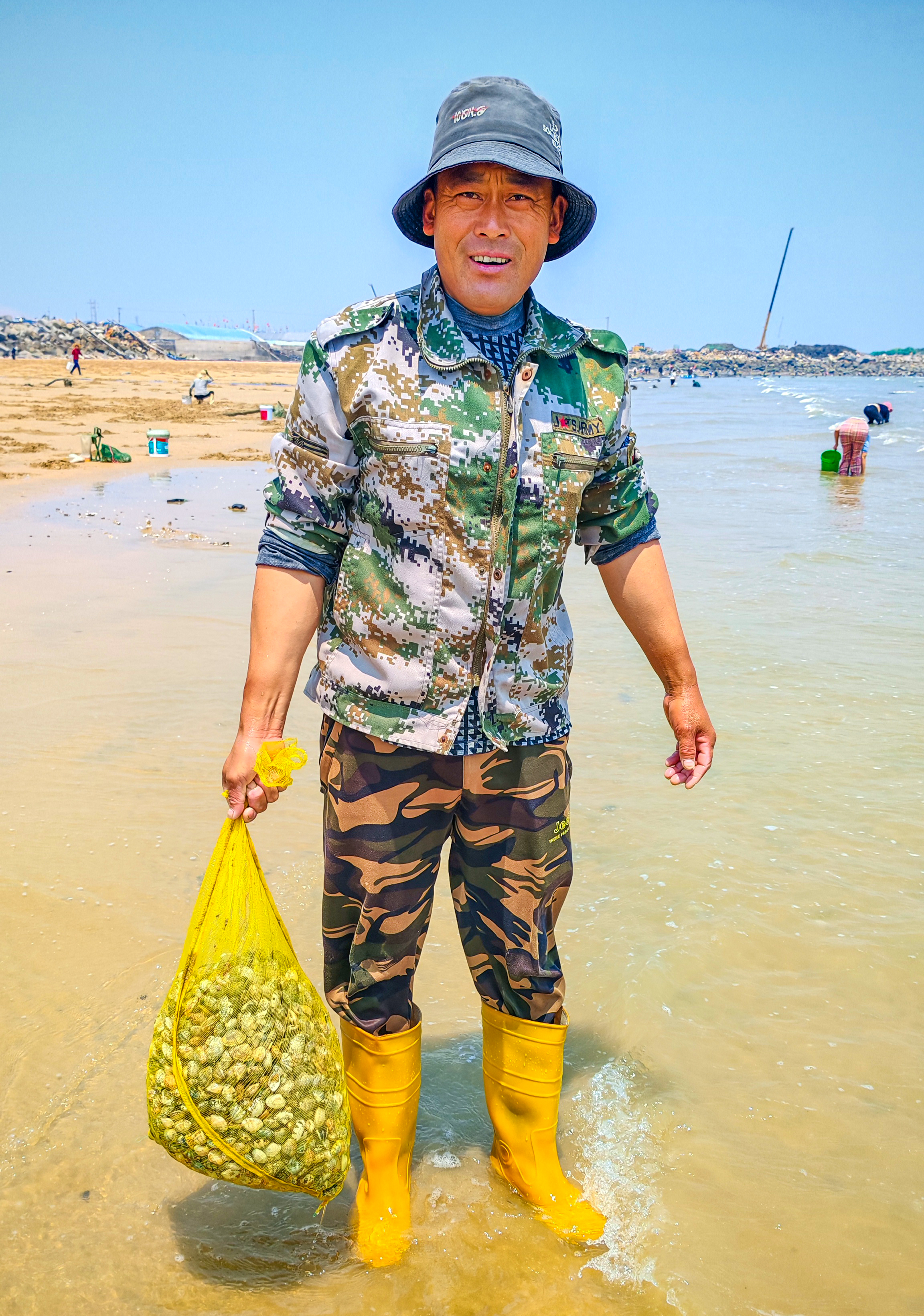 A man is pictured with his catch during a clam outing at a beach in Taoluo Town, Rizhao, Shandong Province on May 11, 2025. /IC  