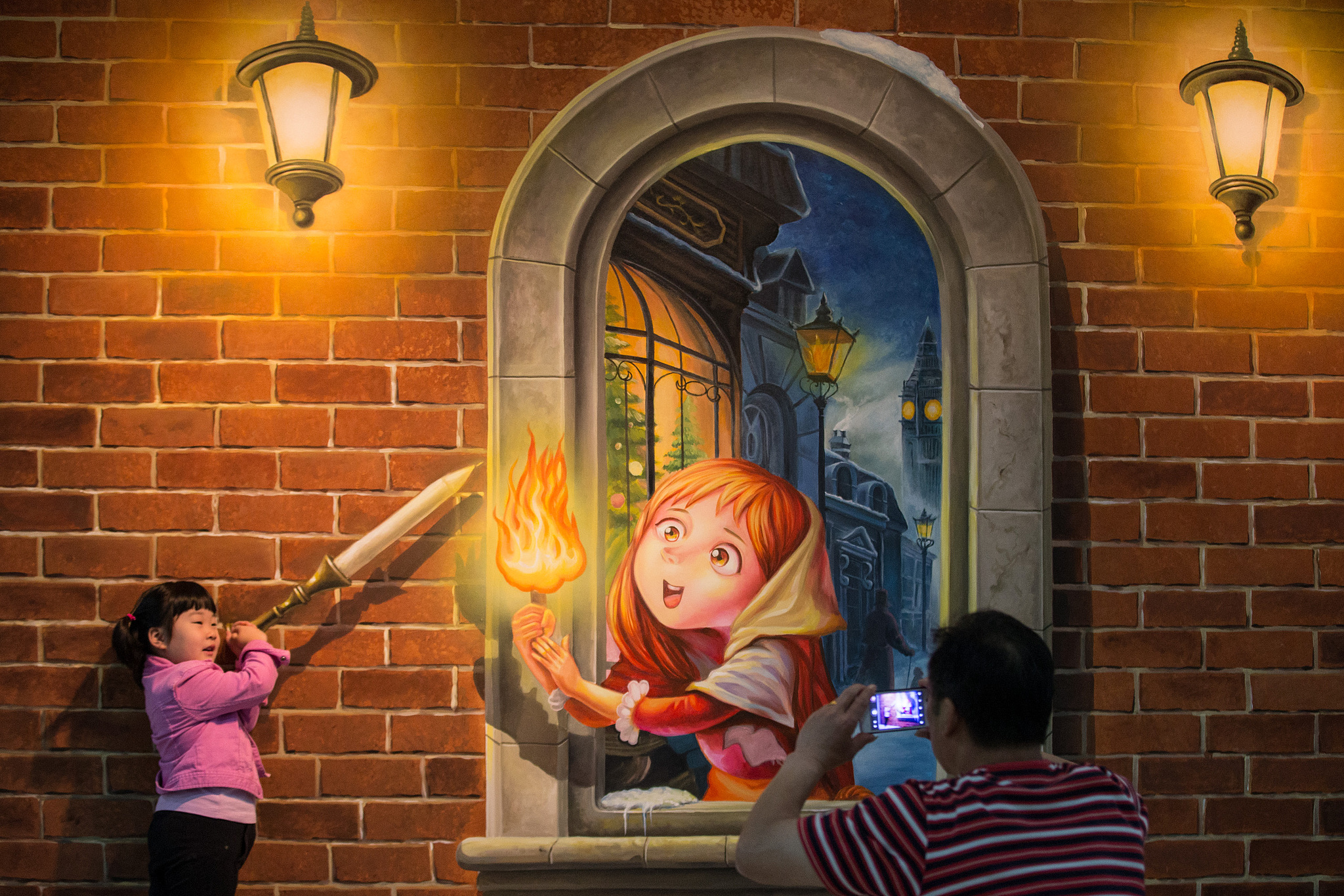 A girl poses for photos in front of a 3D painting of 