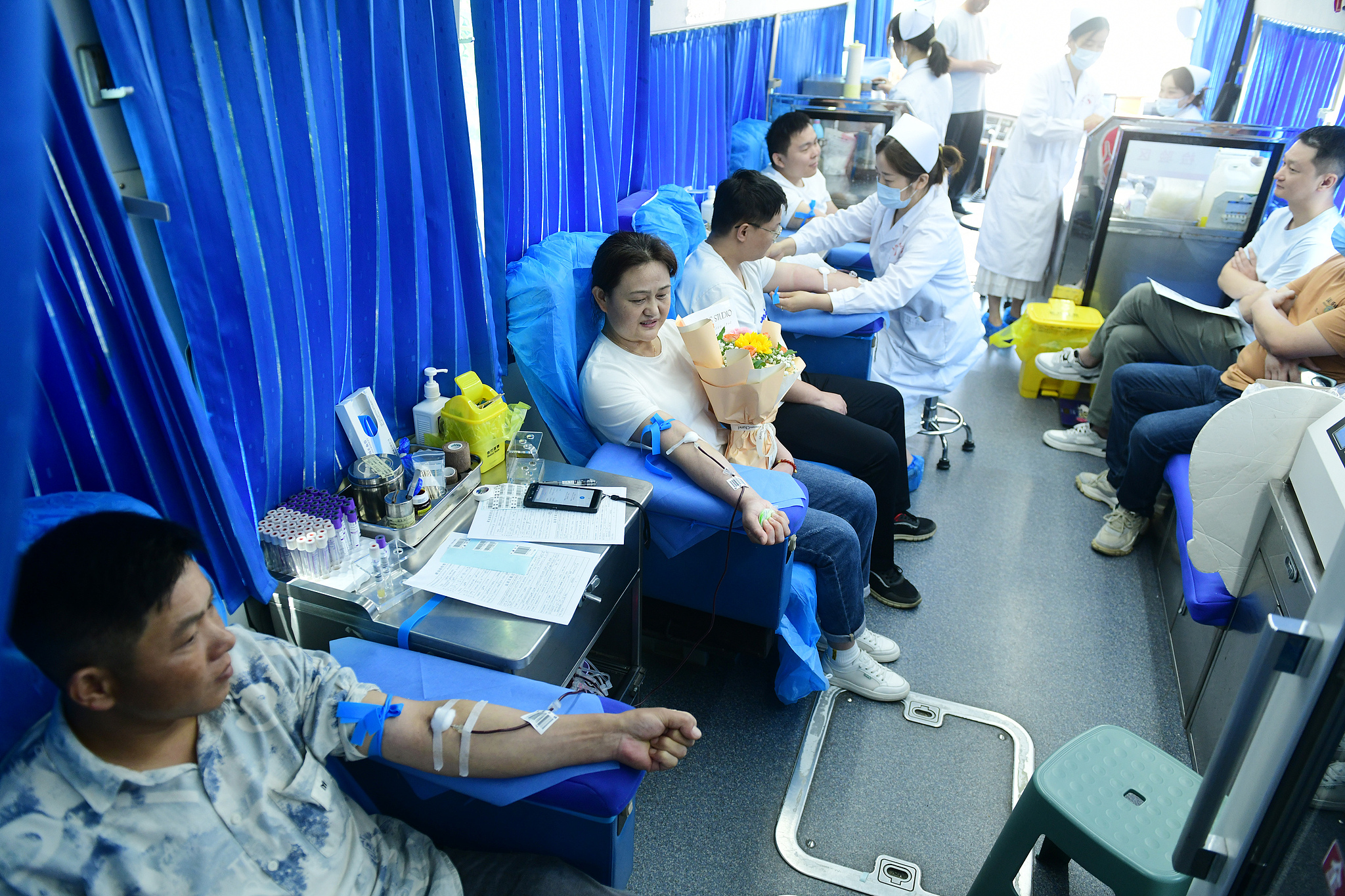 Volunteers donate blood on a blood donation vehicle in Fuyang, east China's Anhui Province, June 13, 2025. /VCG