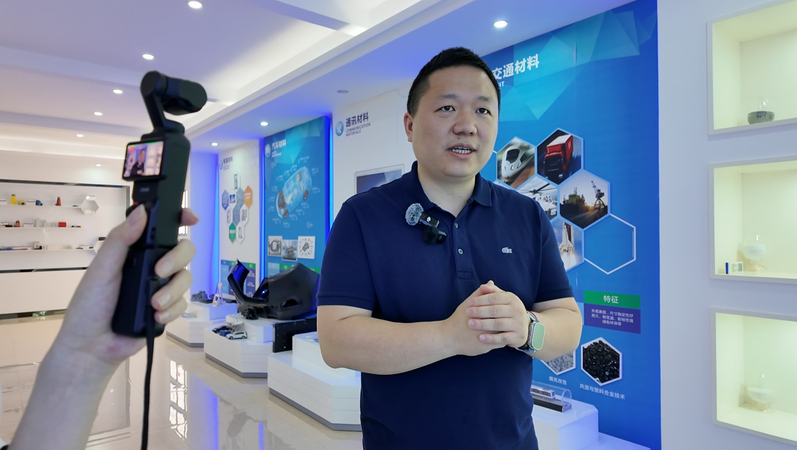 Chen Xiaopeng, vice president of operations at Shiny New Materials, takes reporters on a tour of his company's premises, with promotional materials and applications for its engineered plastics visible in the background, in Wenzhou, Zhejiang Province, June 4, 2025./CGTN