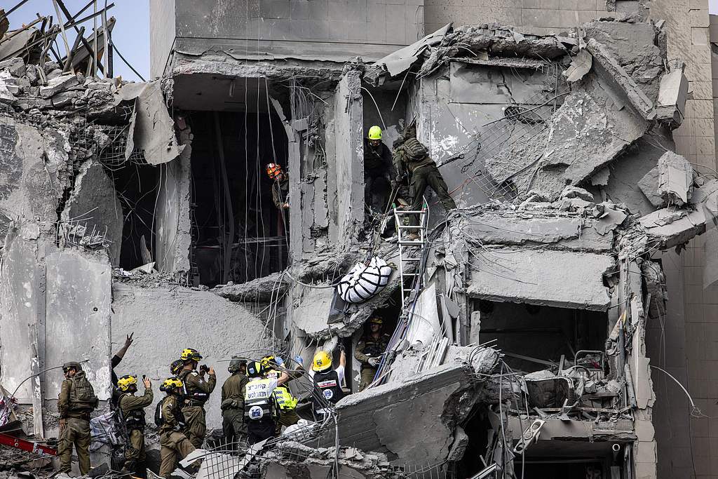 Israeli emergency services and security officers evacuate a body from the rubble of a building hit by an Iranian missile in Beersheba, southern Israel, June 24, 2025. /CFP