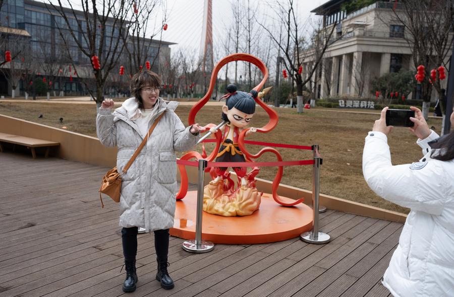 A fan poses for photos with a statue of Nezha, the main character from 
