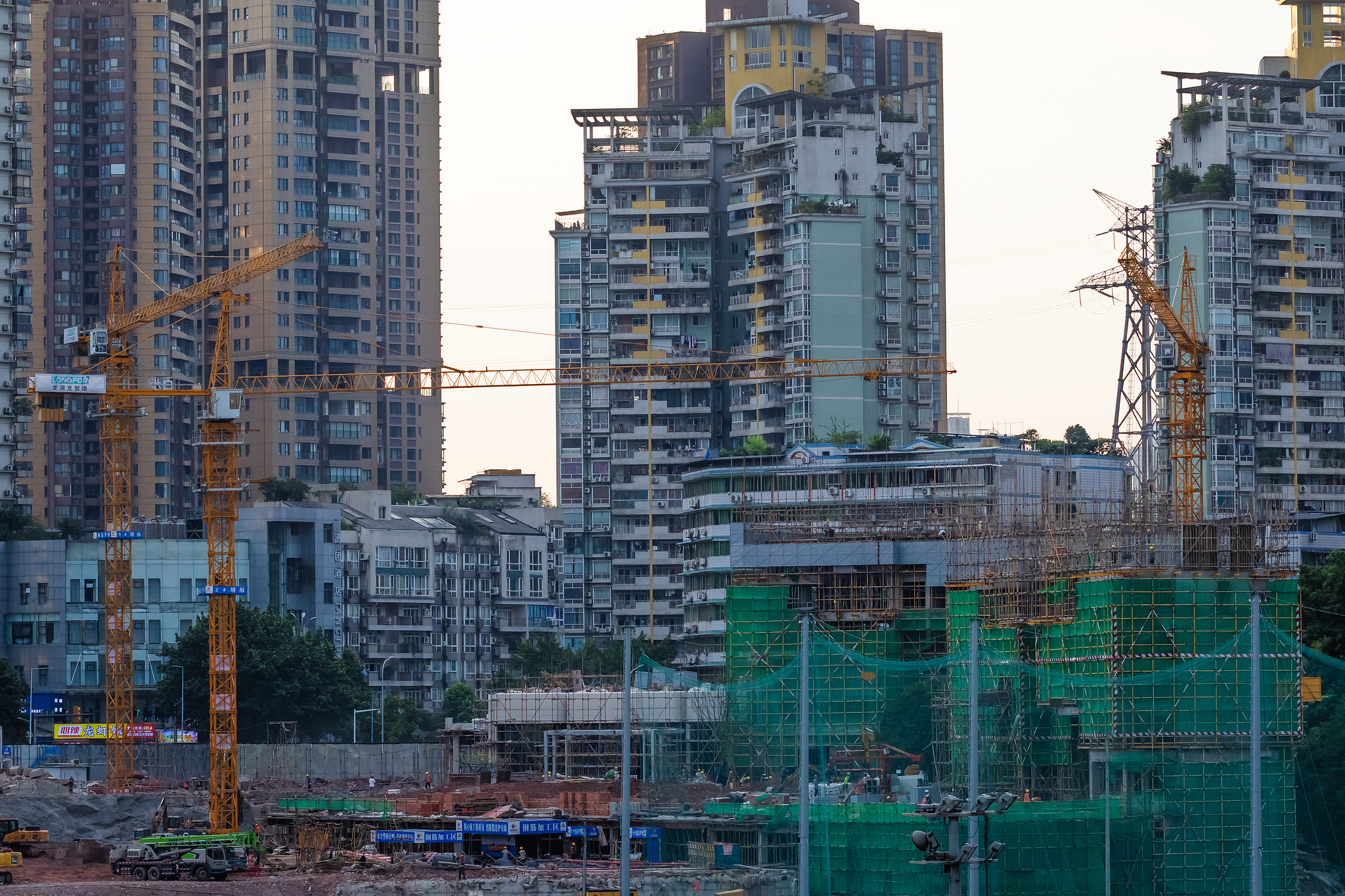 Cranes operate at an urban construction site surrounded by residential and commercial high-rise buildings, as development continues in the densely built city of Chongqing, China, June 5, 2025. /VCG