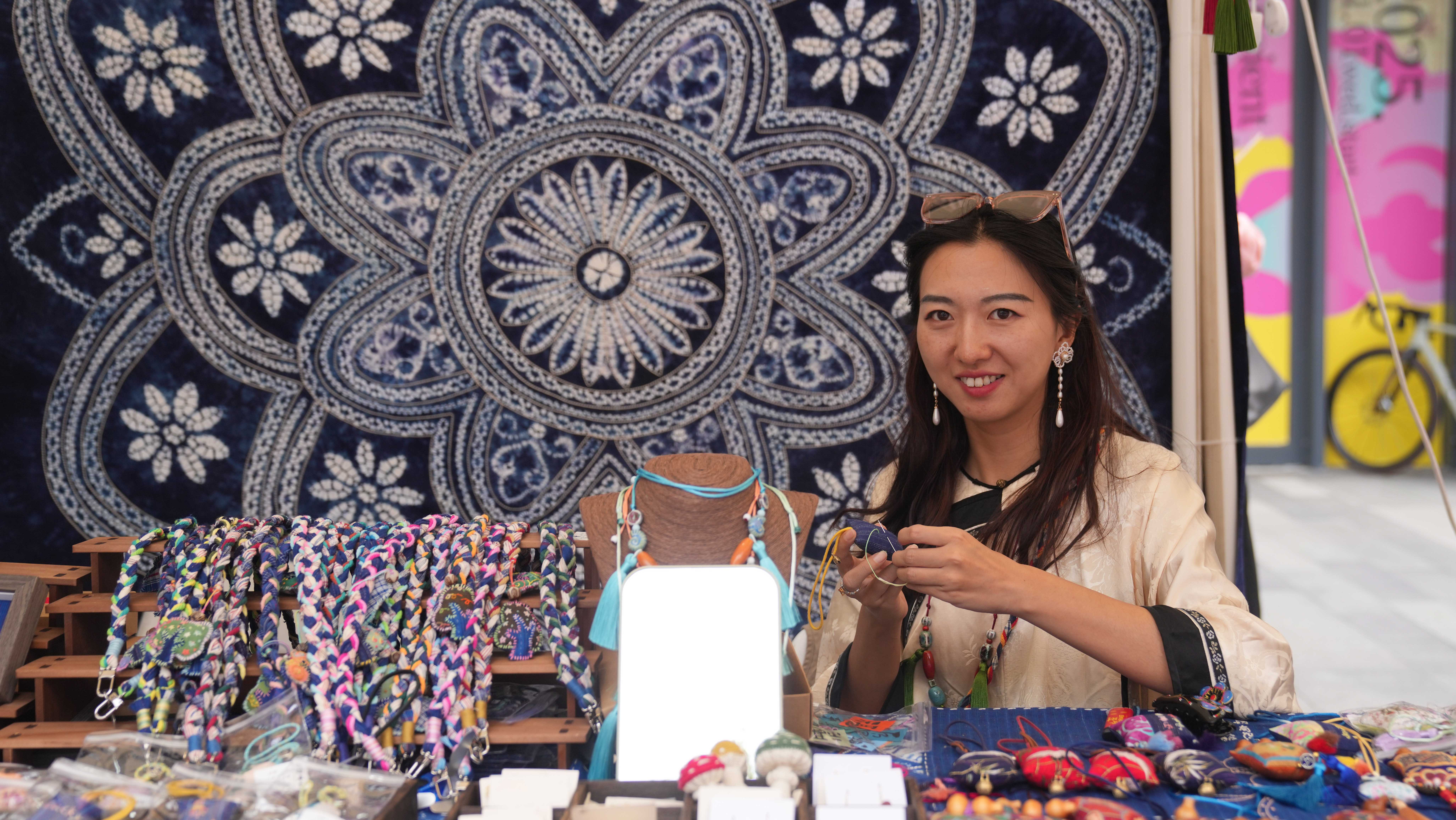 A vendor at a recent Dali fair in Beijing showcases items at her stall. The Dali Bai Autonomous Prefecture in southwest China is home to the Bai ethnic group. Chen Bo/CGTN 