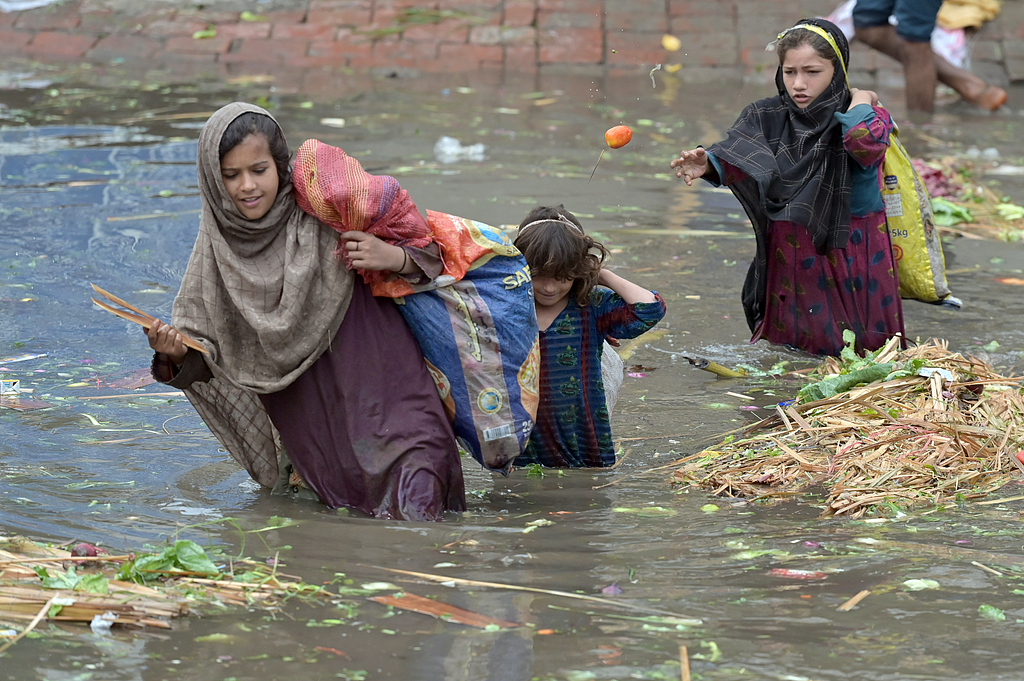 Children walk through a waterlogged street after heavy rainfall in Lahore, Pakistan, 23 July 2025. /CFP