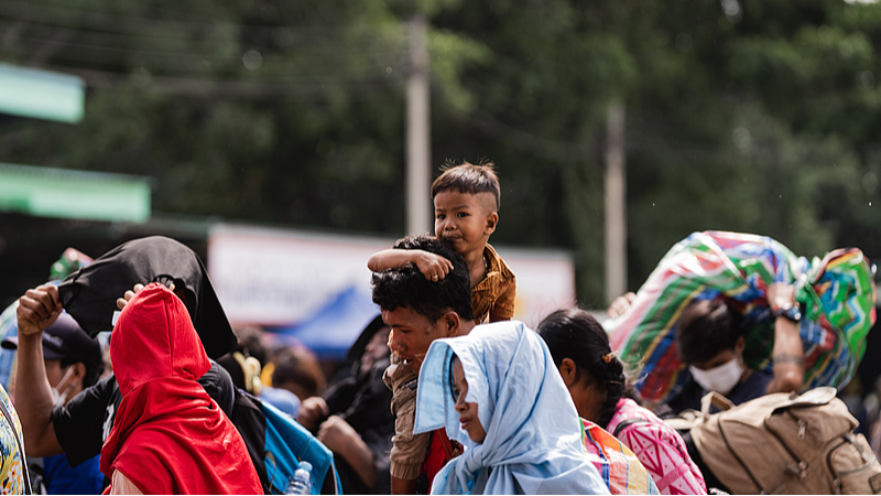 A child clings to his father's shoulders as crowds of Cambodians return home through the Ban Laem checkpoint in Thailand, July 28, 2025. /VCG