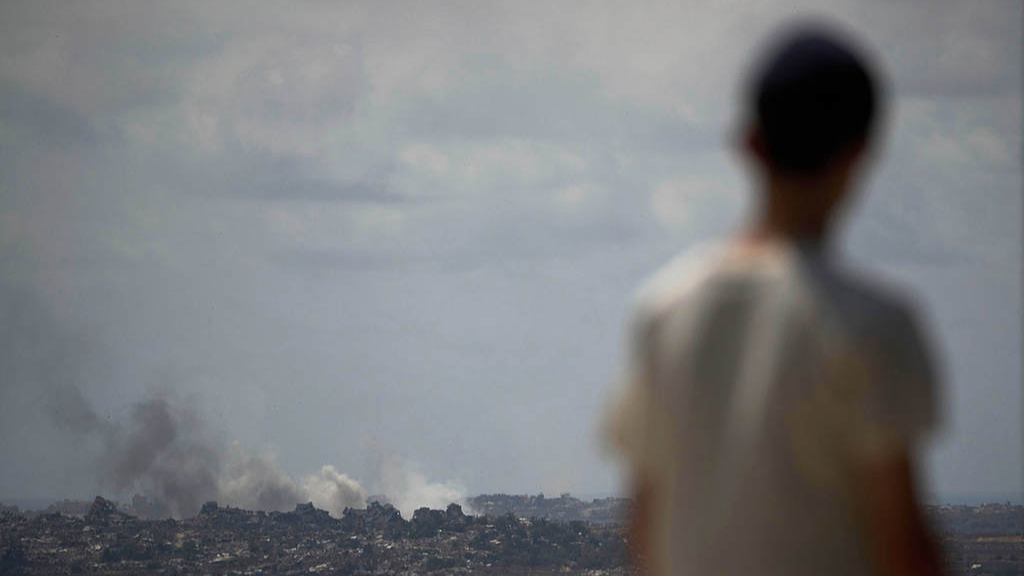 A young man observes smoke rising to the sky after an explosion in the Gaza Strip as he visits a sightseeing area in Sderot, southern Israel, May 22, 2025. /VCG