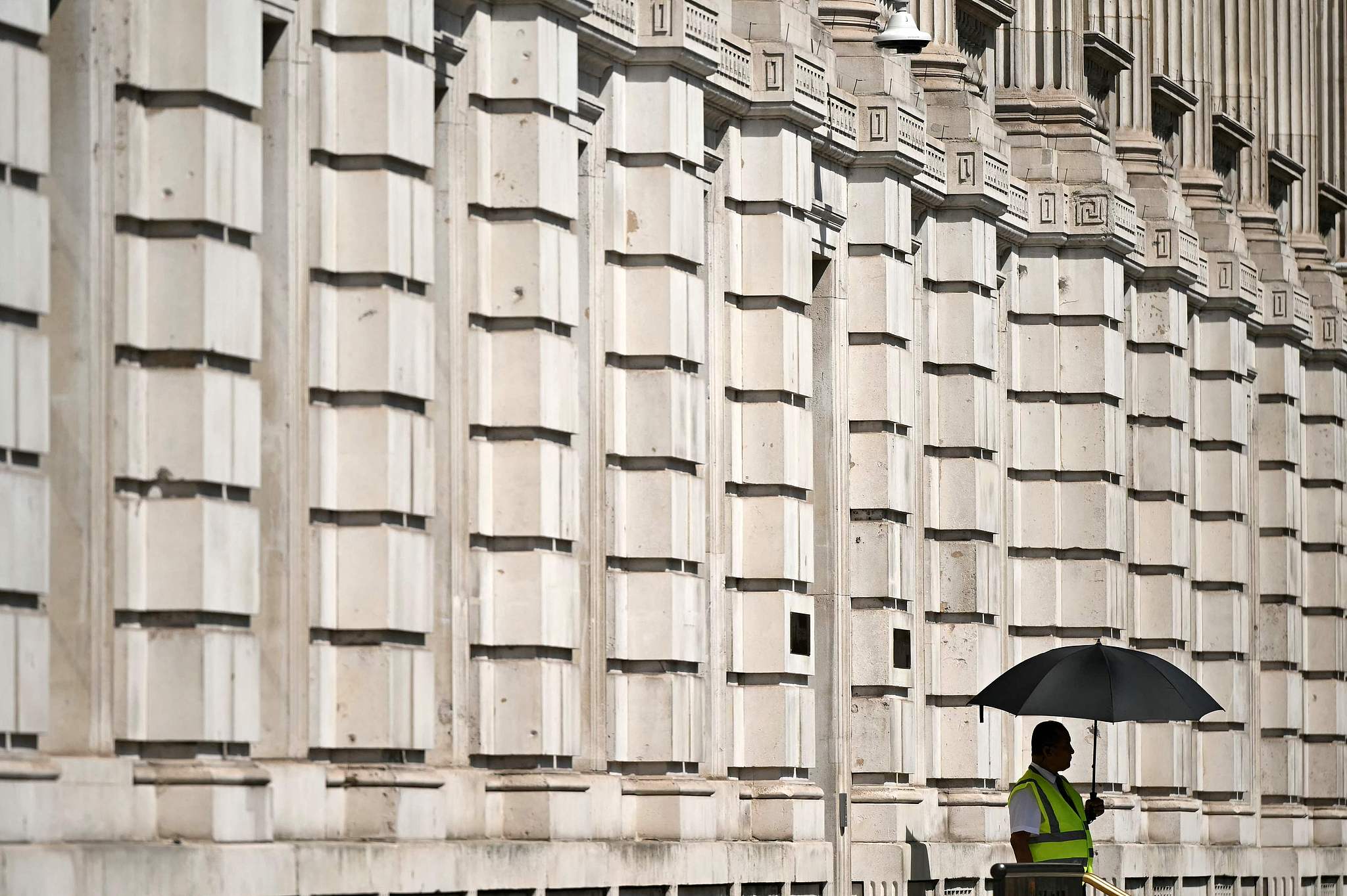 A security guard uses an umbrella to shelter from the heat of the sun whilst standing on duty outside of the Cabinet Office on Whitehall in London, UK, July 1, 2025. /VCG