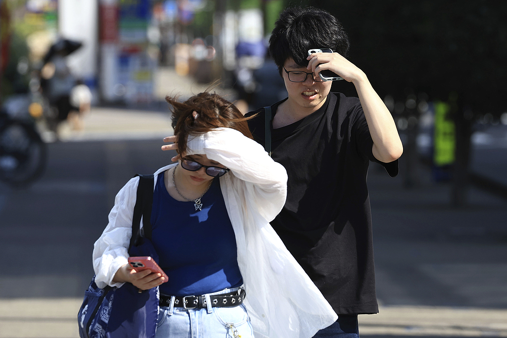 People walk in the scorching heat, shielding themselves from the sun, in Shizuoka City, Japan, August 4, 2025. /CFP