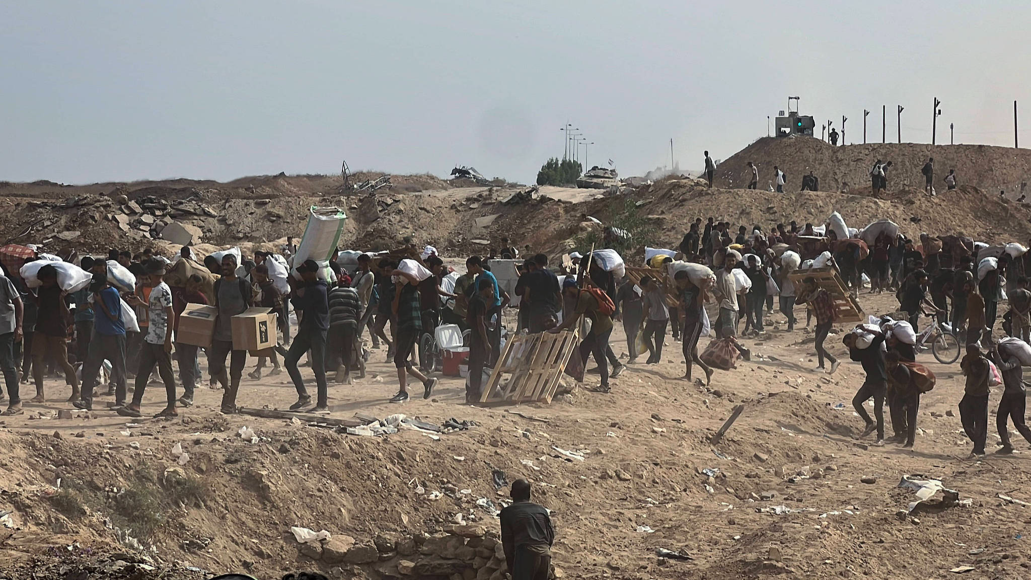 Displaced Palestinians struggling with hunger flock to an aid distribution point set up in the Netzarim Corridor in hopes of receiving limited humanitarian aid in Deir al Balah, Gaza, August 12, 2025. /VCG