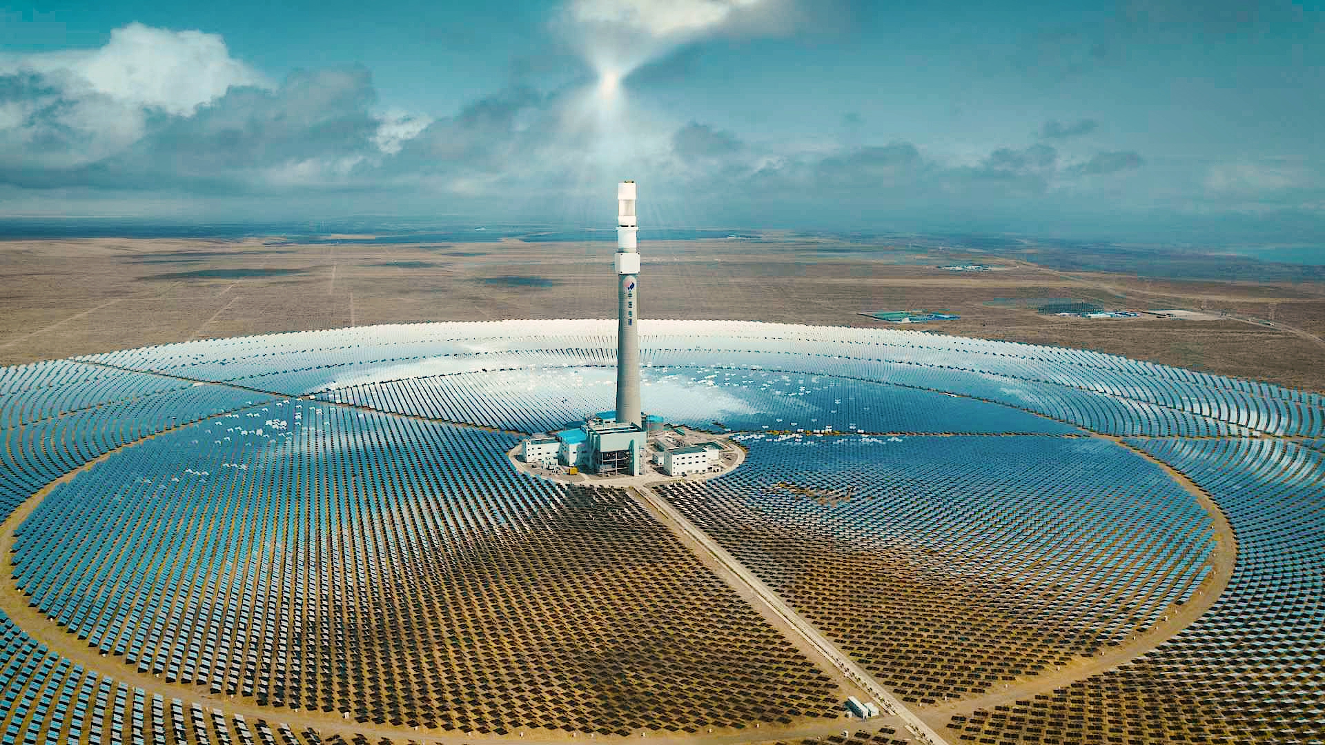 A solar power tower stands tall amidst a field of solar panels. This photovoltaic power station is currently one of the world's largest solar power plants. /By Huang Chengde, CGTN