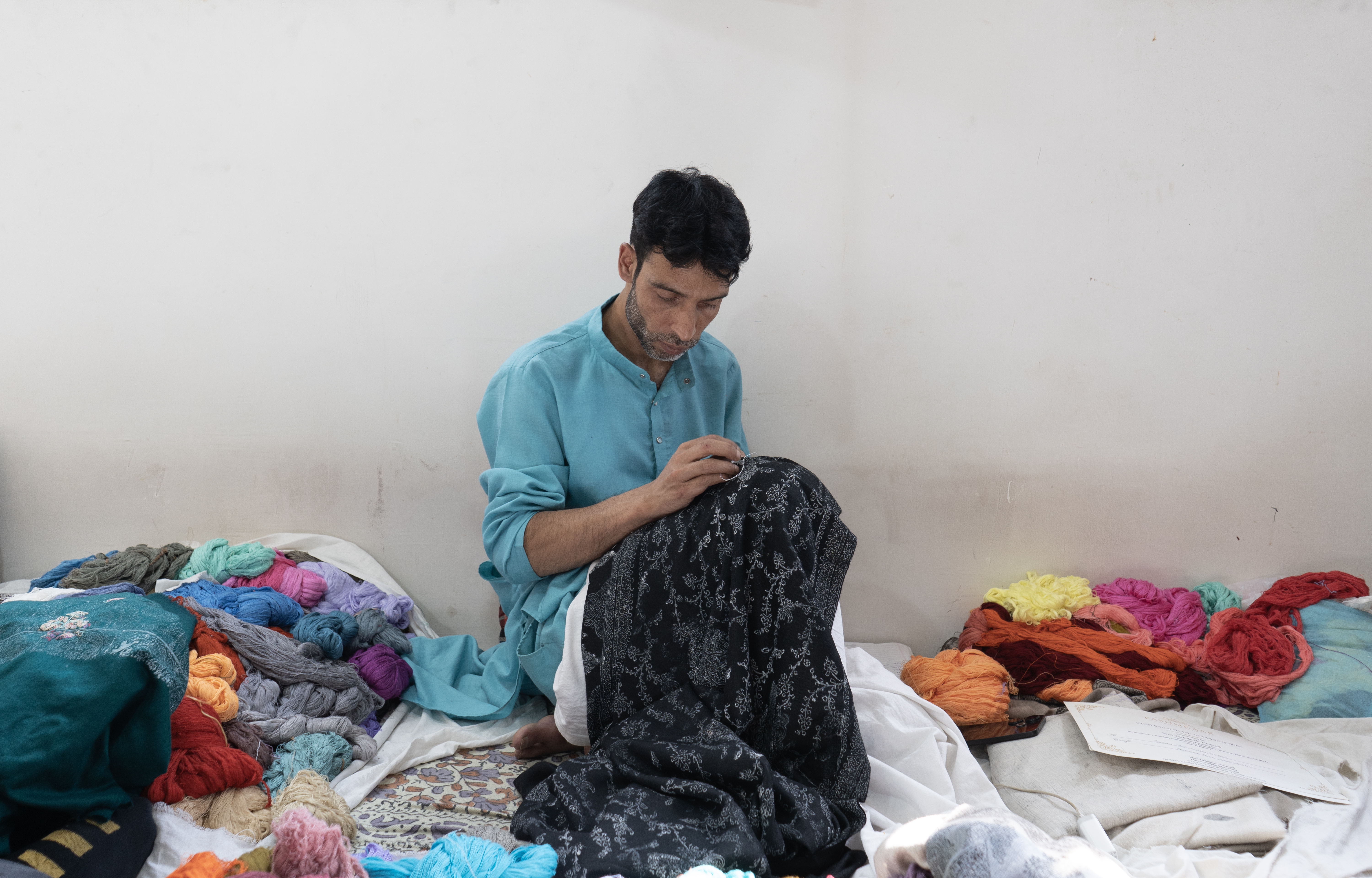An artisan works on an unfinished shawl at the workshop of Pashmkaar Kashmir, a leading manufacturer and exporter of pashmina shawls, in the Hazratbal area of Srinagar, Indian-administered Kashmir. August 4, 2025. 