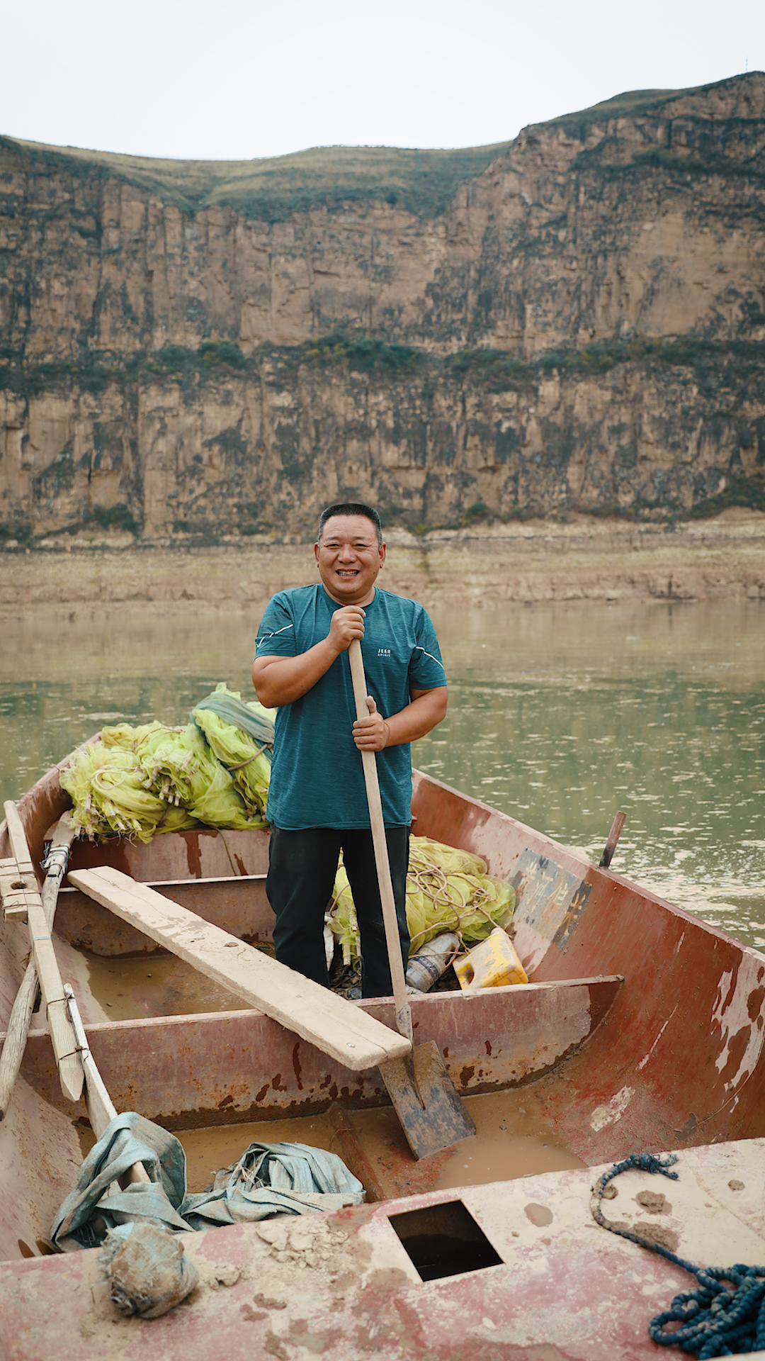 Guo Shuaisheng poses for a photo in his boat. Rowing boats and fishing used to be the traditional way of life in Laoniuwan, but the local villagers no longer rely on them for a living. Yet, Guo Shuaisheng sometimes reverts to his old hobby of catching fish for his customers. /CGTN