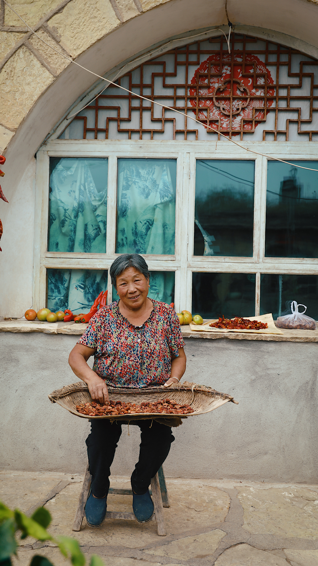 Guo Shuaisheng’s mother sorts dried fruit in her courtyard. She lives next to her son's hostel and grows a variety of vegetables, flowers, and fruit in her garden. /CGTN