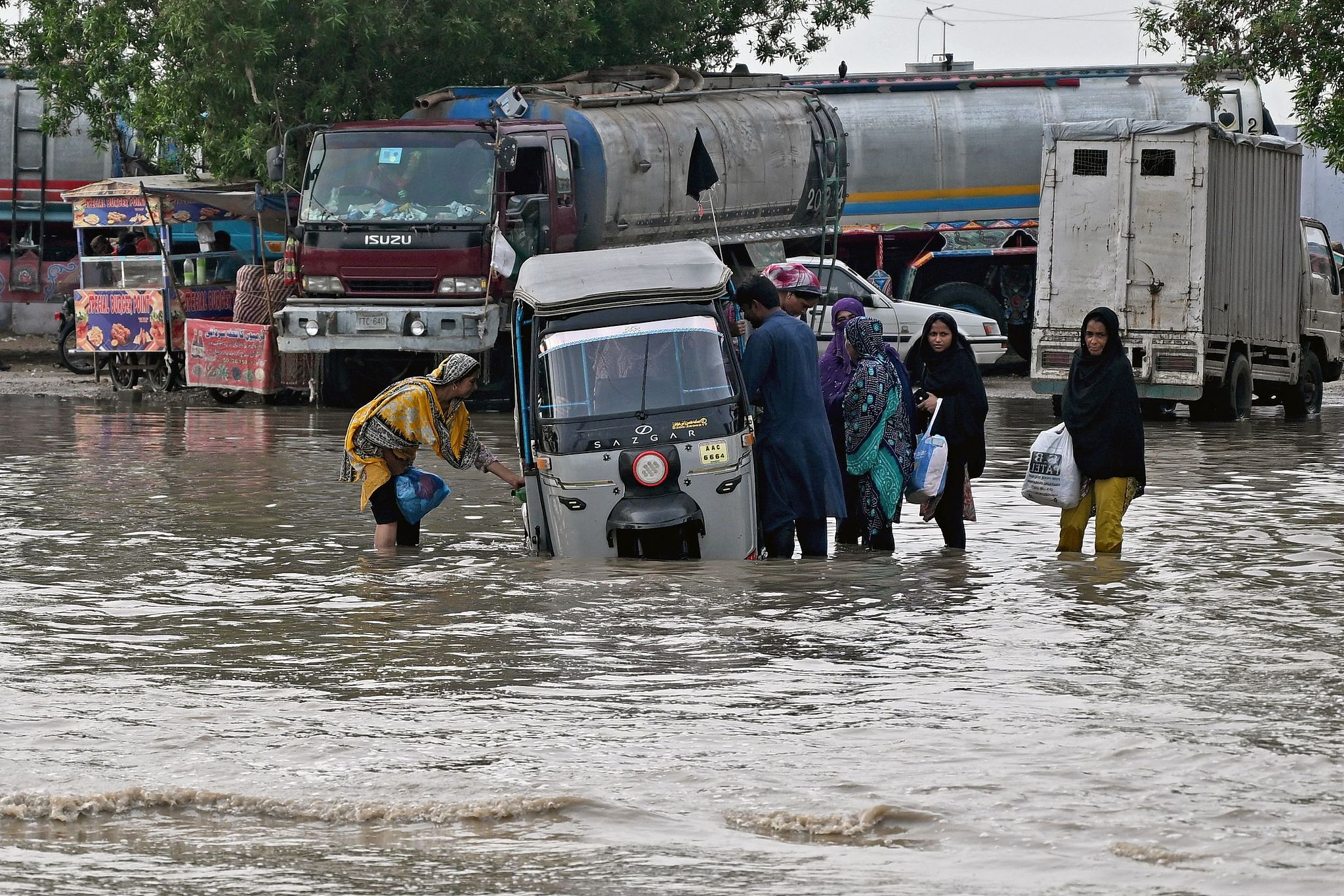 Passengers disembark from an auto rickshaw that got stranded on a flooded road after heavy monsoon rains in Karachi, Pakistan, August 20, 2025. /VCG