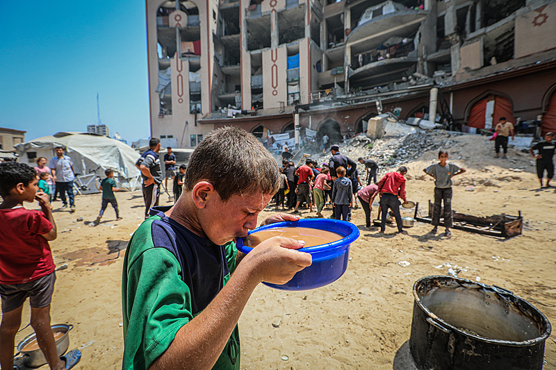 A Palestinian child has soup distributed by a charity amid the rubble in Gaza City, Palestine, August 16, 2025. /VCG