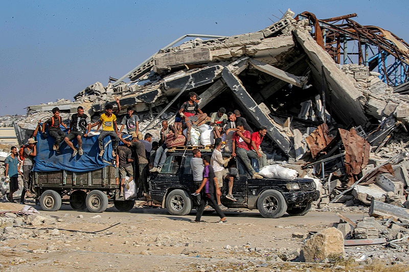 People ride atop a vehicle towing a cart behind, both loaded with bags of humanitarian aid in the central Gaza Strip, Palestine, August 22, 2025. /VCG