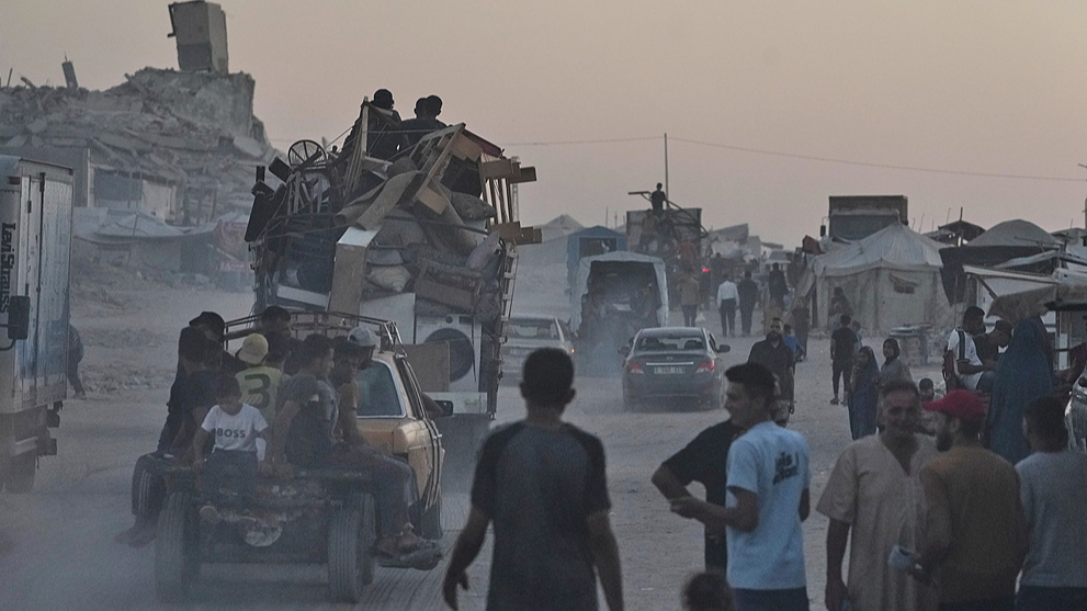 Palestinians transport their belongings past a displacement camp along the beach in Gaza City, August 23, 2025. /VCG
