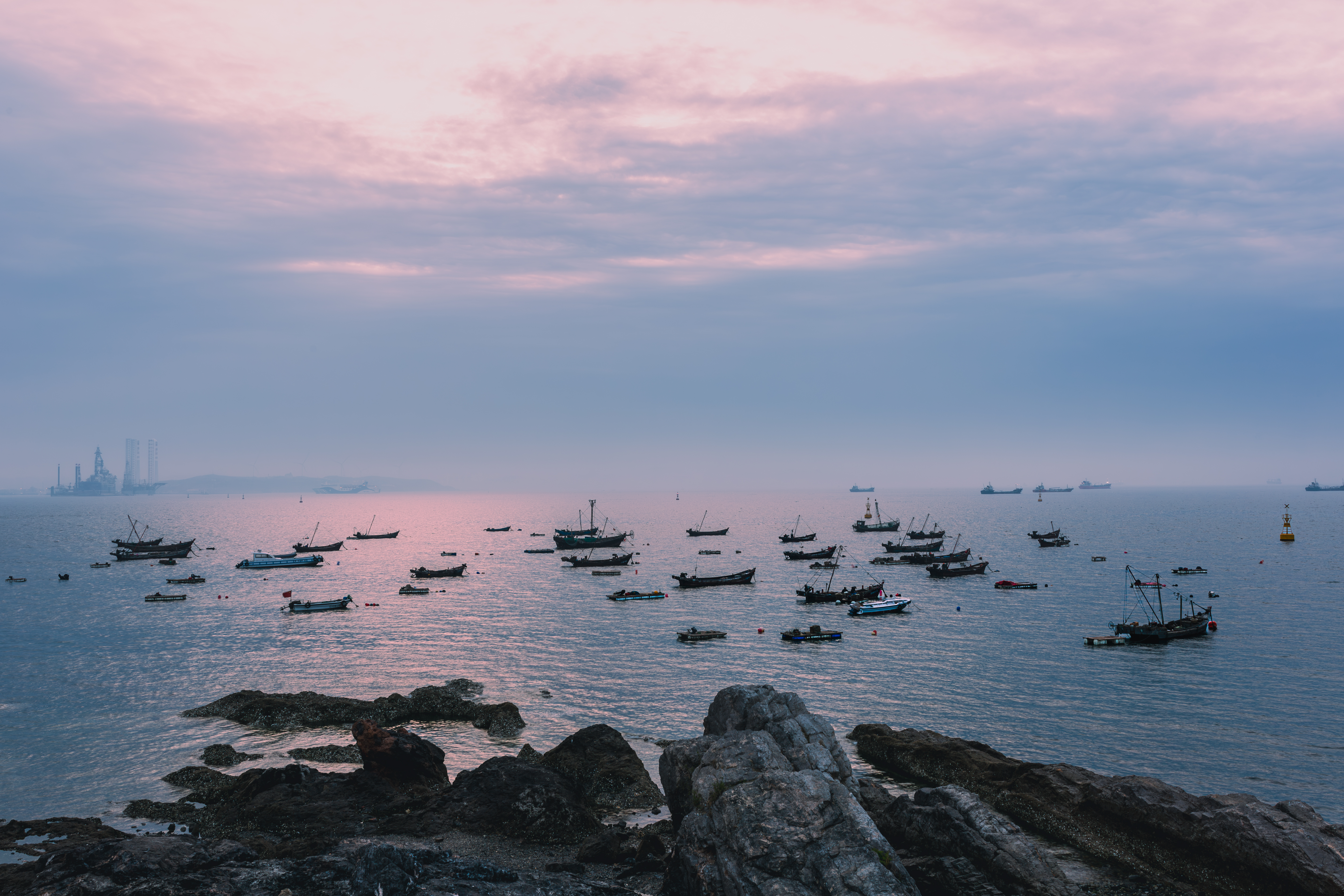 Harbor: The morning sun's glow reflects on the calm bay, where fishing boats are quietly moored, and the reefs along the shore stand watch in silence. The work, titled 