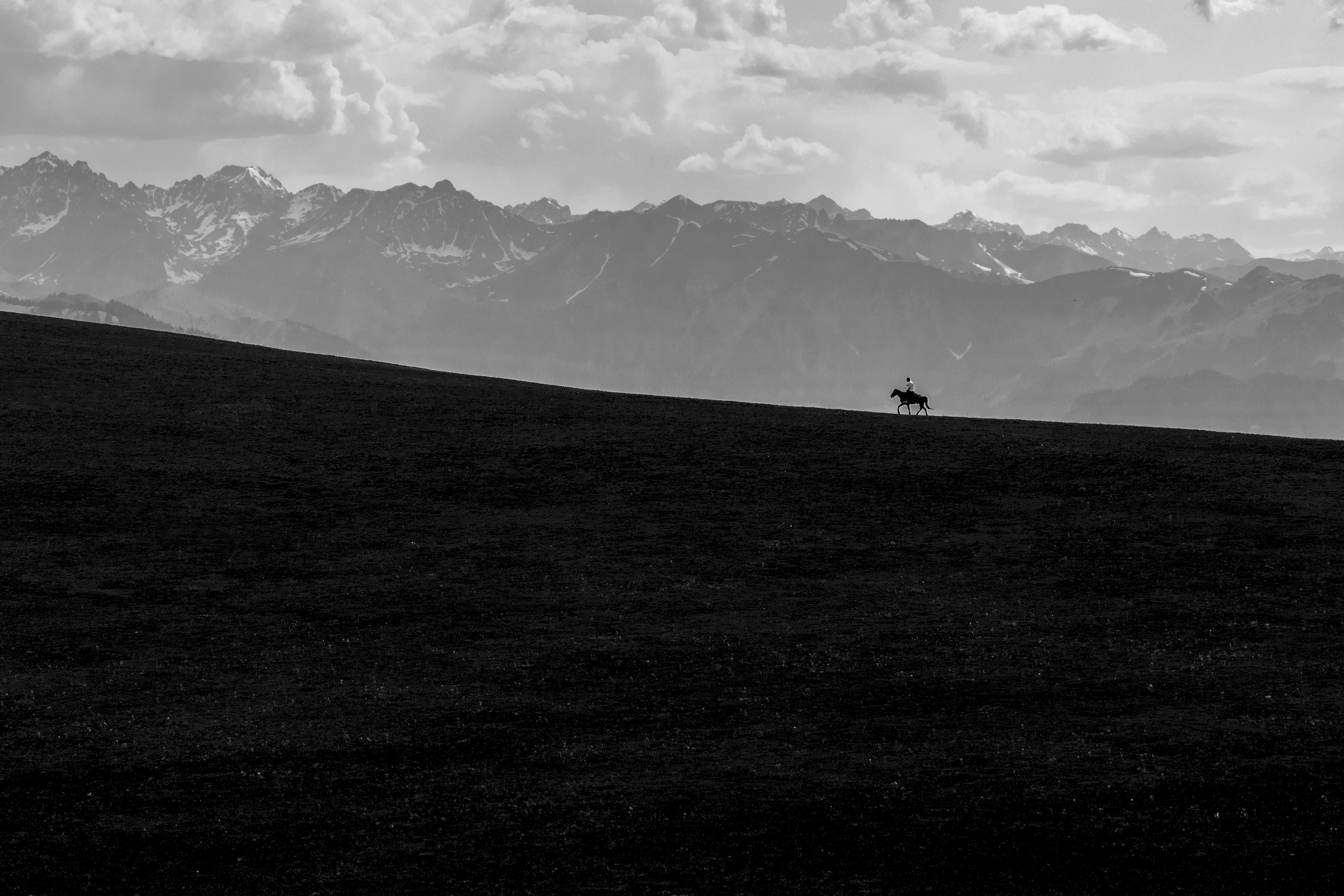 Across the Mountain: Between heaven and earth, a lone rider and horse press forward with unwavering resolve. The vast grasslands stretch toward snow-capped mountains, revealing the grandeur and majesty of the land. This image captures the spirit of a child of nature, conveying a profound sense of responsibility for the earth – cherishing every inch of soil and safeguarding a home where all life coexists. Such stewardship concerns not only ecological balance but also the sustainable development of human society. When we respect nature and promote fairness and shared prosperity, this responsibility transcends borders and cultures, becoming a force that drives the world toward a more harmonious future. /Huang Lin