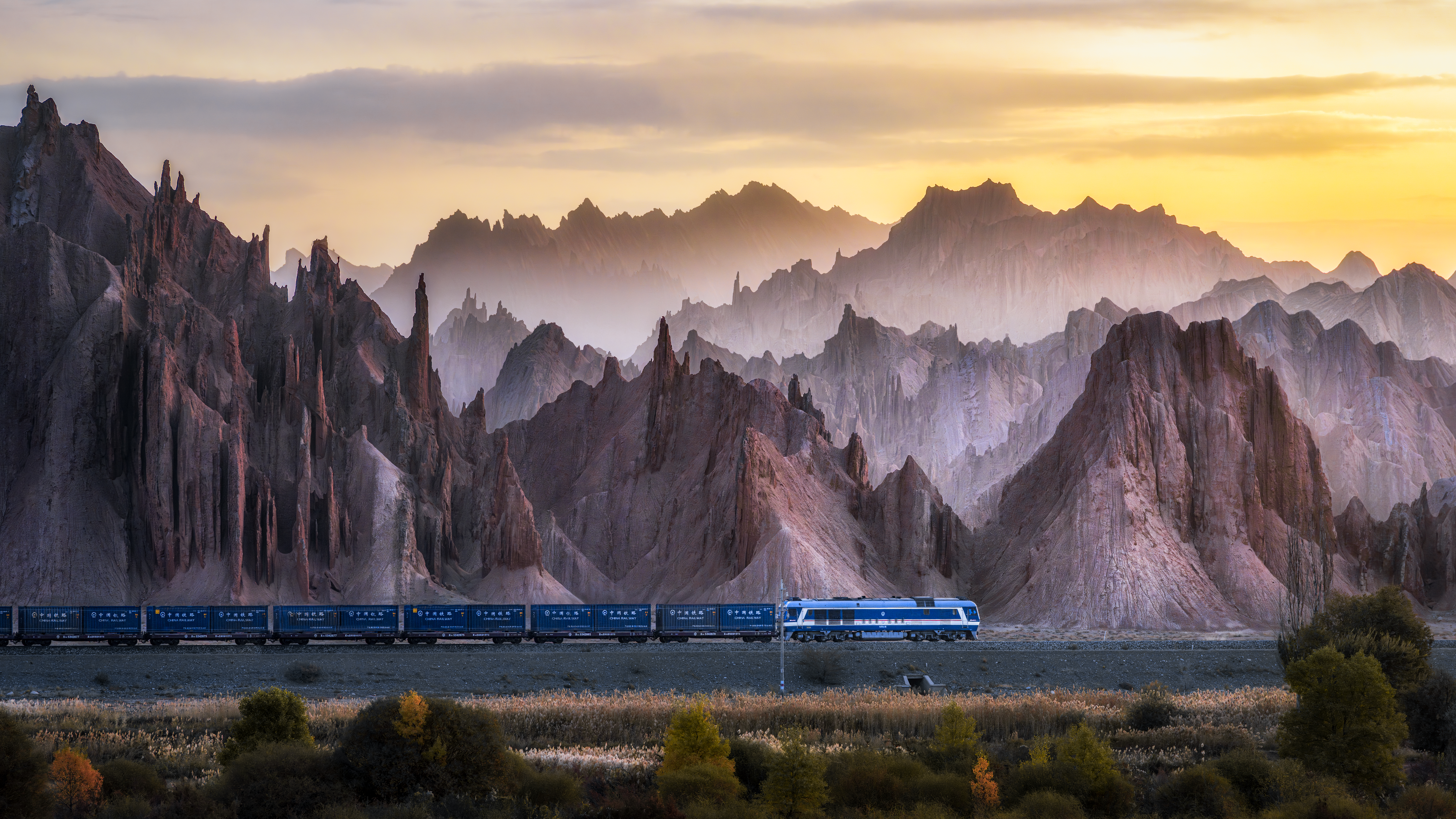 The Train Through Marvels: In the early morning, a freight train shuttles through the Hongshan Stone Forest in Xinjiang. I recorded this scene with my camera. It is a microcosm of the integration of industrial innovation and poverty reduction. Infrastructure projects such as China Railway build bridges for the circulation of goods and empower industrial upgrading, turning 