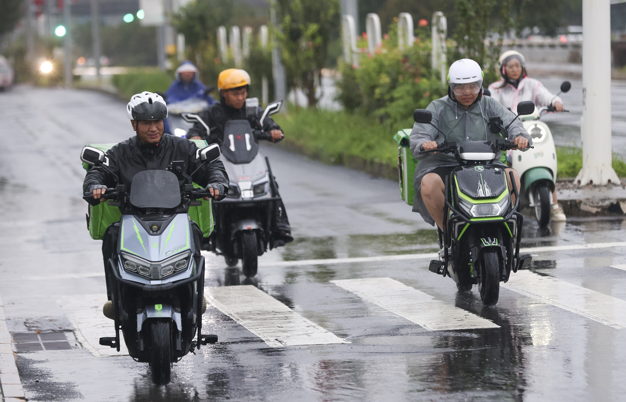 Food delivery workers on motorbikes in the rain, Beijing, China, August 8, 2025. /CFP