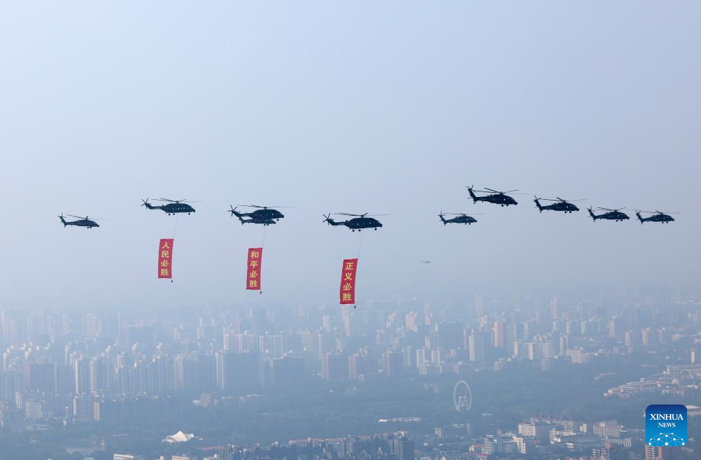 Helicopters fly over Tian'anmen Square carrying banners that read 