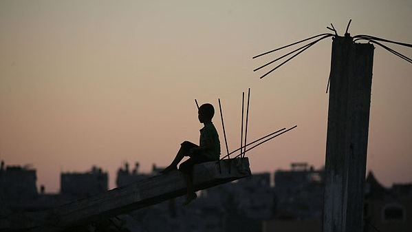 A Palestinian child is silhouetted as he sits on the debris of a destroyed building in the Bureij camp for displaced Palestinians in central Gaza Strip, September 3, 2025. /VCG
