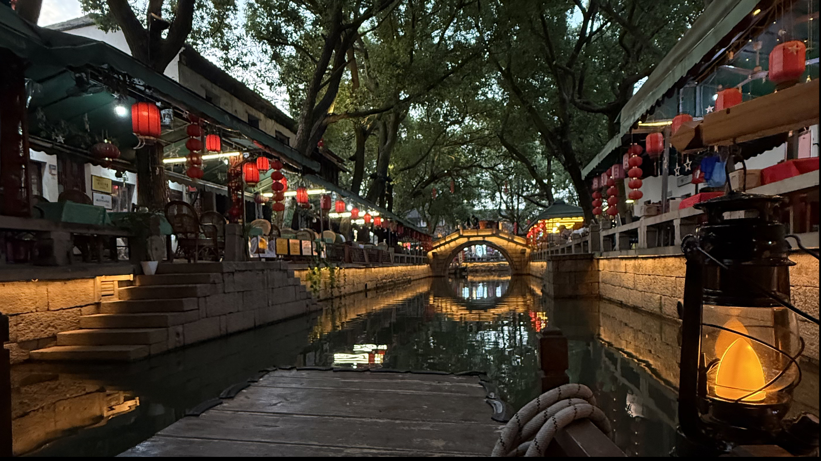 A wooden boat drifts along the canal, as music and chatter spill from cafés on the banks, Tongli Water Town, Jiangsu Province. /Zaruhi Poghosyan