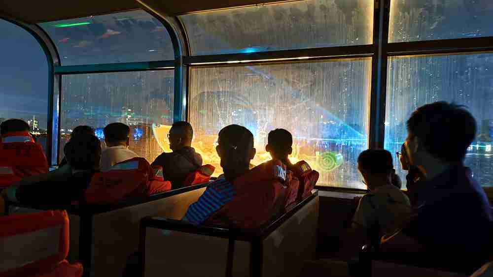 On Shifeng Lake in Tiantai County, Taizhou City, Zhejiang Province in China, a night cruise boat carries tourists forward slowly. A water curtain projection showcases the performance 