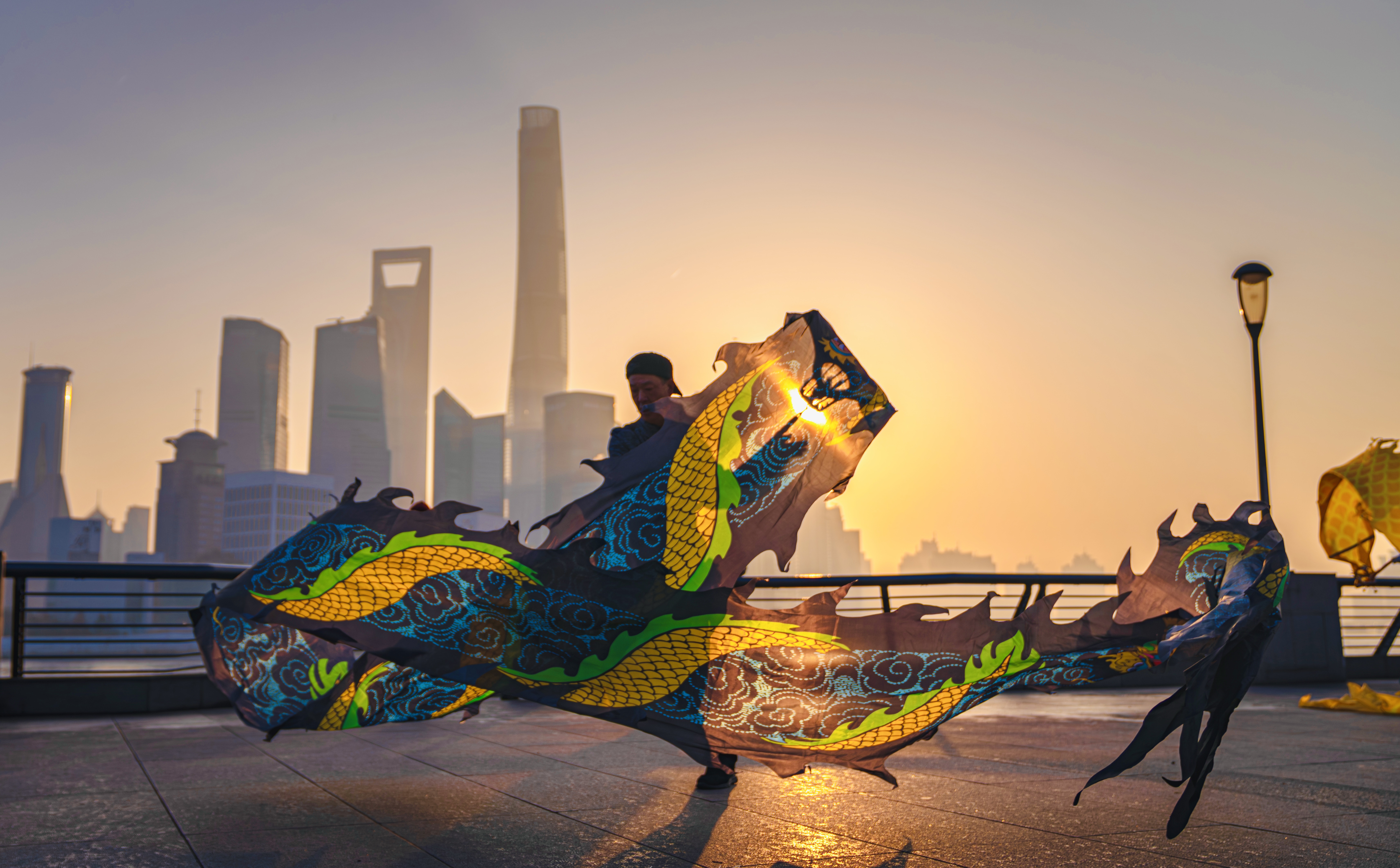 On the first morning of 2024, sunlight scattered like gold dust over the Bund. Dragon dancers leaped with vibrant energy, their gilded scales shimmering in the dawn light, weaving between the metallic outlines of modern skyscrapers. This scene embodies the UN Sustainable Development Goal of 