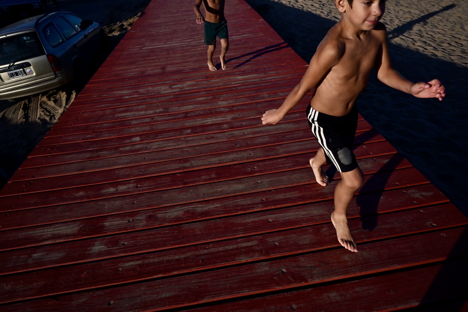 Tide of Us: Tide of Us is a portrait of daily life at the water's edge, joyful, tender, mundane. Across generations and bodies, these images trace how people gather, rest, kiss, tan, and age in the sunlit proximity of the ocean. Yet behind the playfulness lies quiet unease: foamed shorelines, overexposed skin, a popcorn cart marooned in the tide. The sea is present, but not pristine, it is lived in, leaned on, and increasingly strained. This series does not dramatize catastrophe; instead, it reflects on how the ocean has become a stage for both celebration and silent transformation. In observing leisure, we witness dependency. In photographing comfort, we hint at fragility. These moments remind us: the ocean is not a backdrop, it is a breathing presence, shaping the rhythms of life, and asking in return to be protected. /Daniela Spina