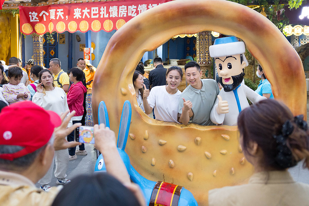 Tourists pose for photos at the Xinjiang International Grand Bazaar on September 10, 2025. /VCG