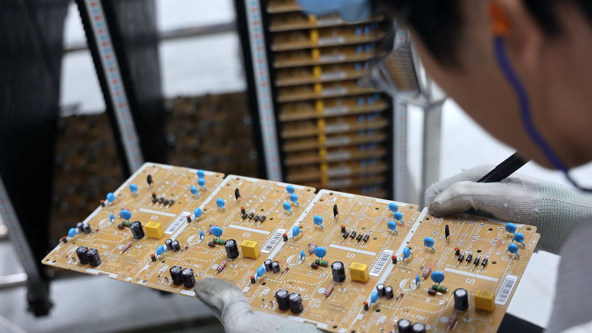 An employee examines a circuit board at a factory in Shandong Province, China, September 9, 2025. /VCG