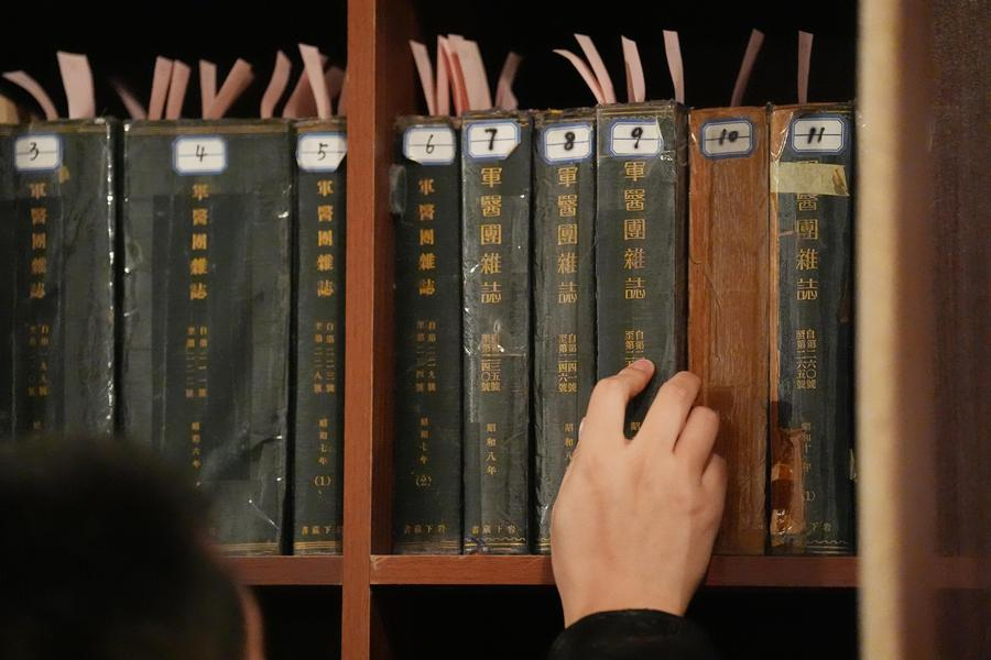 A researcher of the Exhibition Hall of Evidence of Crimes Committed by Unit 731 of the Japanese Imperial Army arranges the original Japanese medical journals at the former site of the headquarters of Unit 731 in Harbin, northeast China's Heilongjiang Province, December 12, 2024. /Xinhua