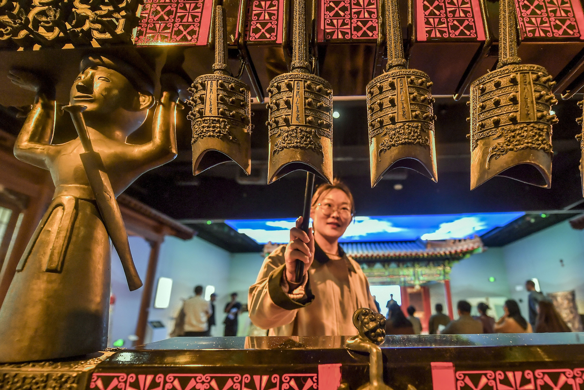 A woman taps ancient bronze chimes at the Xinjiang Intangible Cultural Heritage Museum on September 26, 2025. /VCG