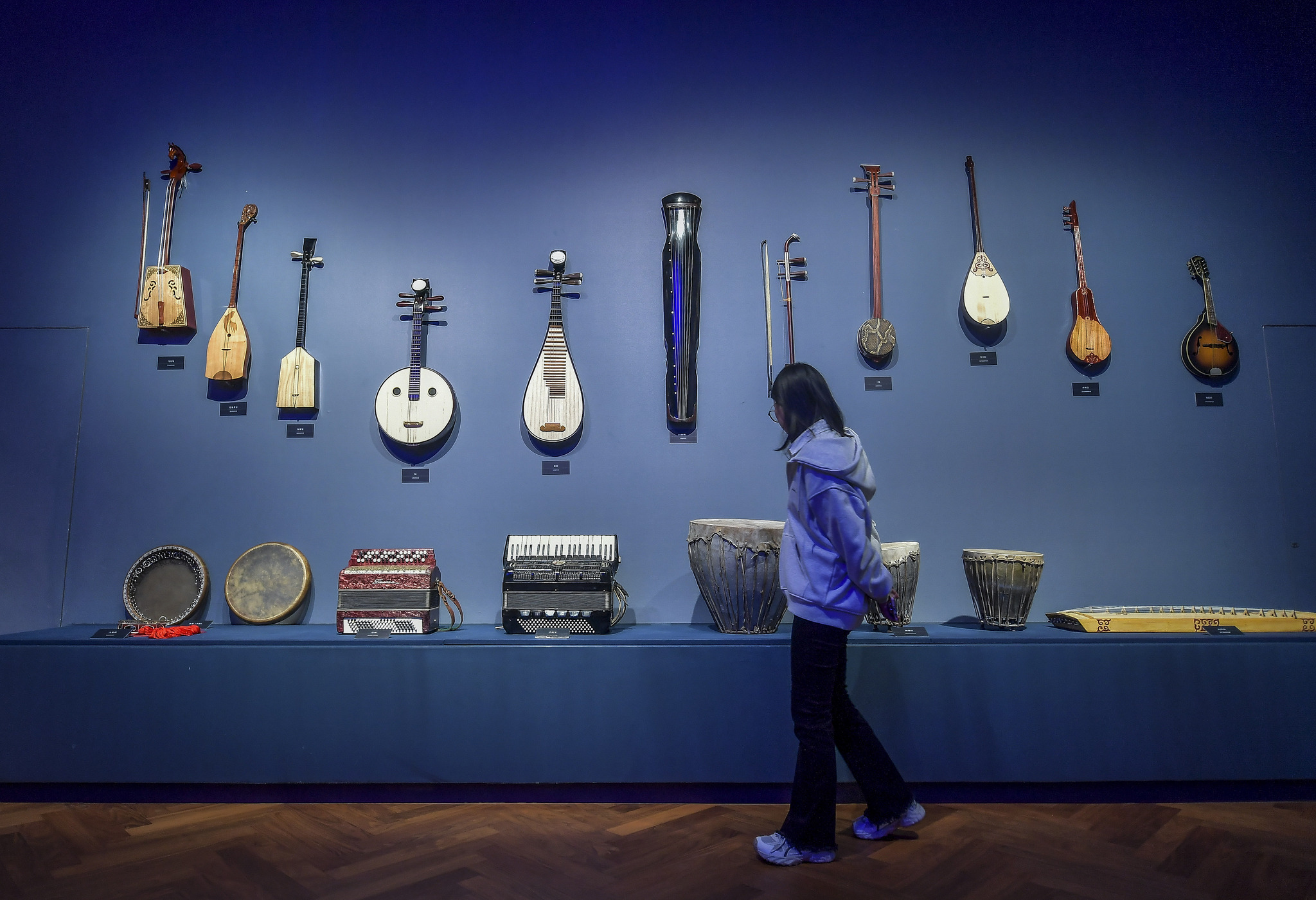 A woman looks at music instruments displayed at the Xinjiang Intangible Cultural Heritage Museum on September 26, 2025. /VCG