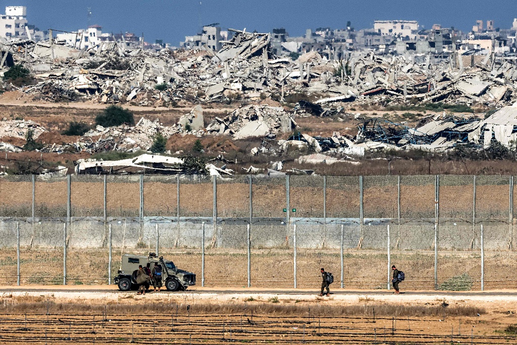 Israeli army soldiers walk towards an armored vehicle at a position along the border fence with the Gaza Strip, September 30, 2025. /CFP